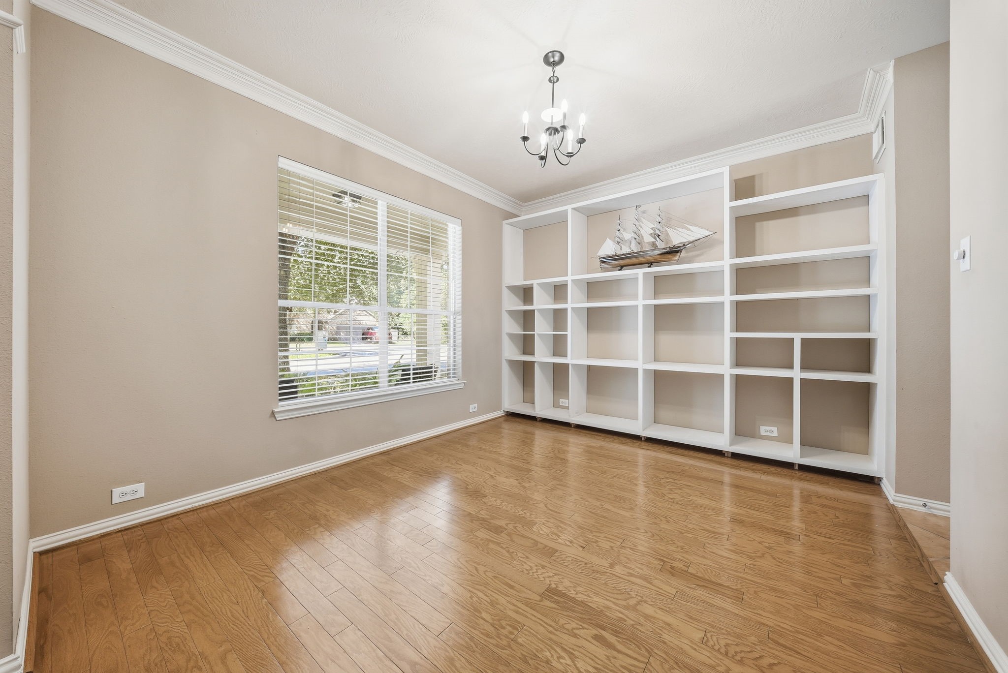 Versatile formal dining space with built-ins offers flexibility for a home office, while a large window brings in natural light and overlooks the front yard.