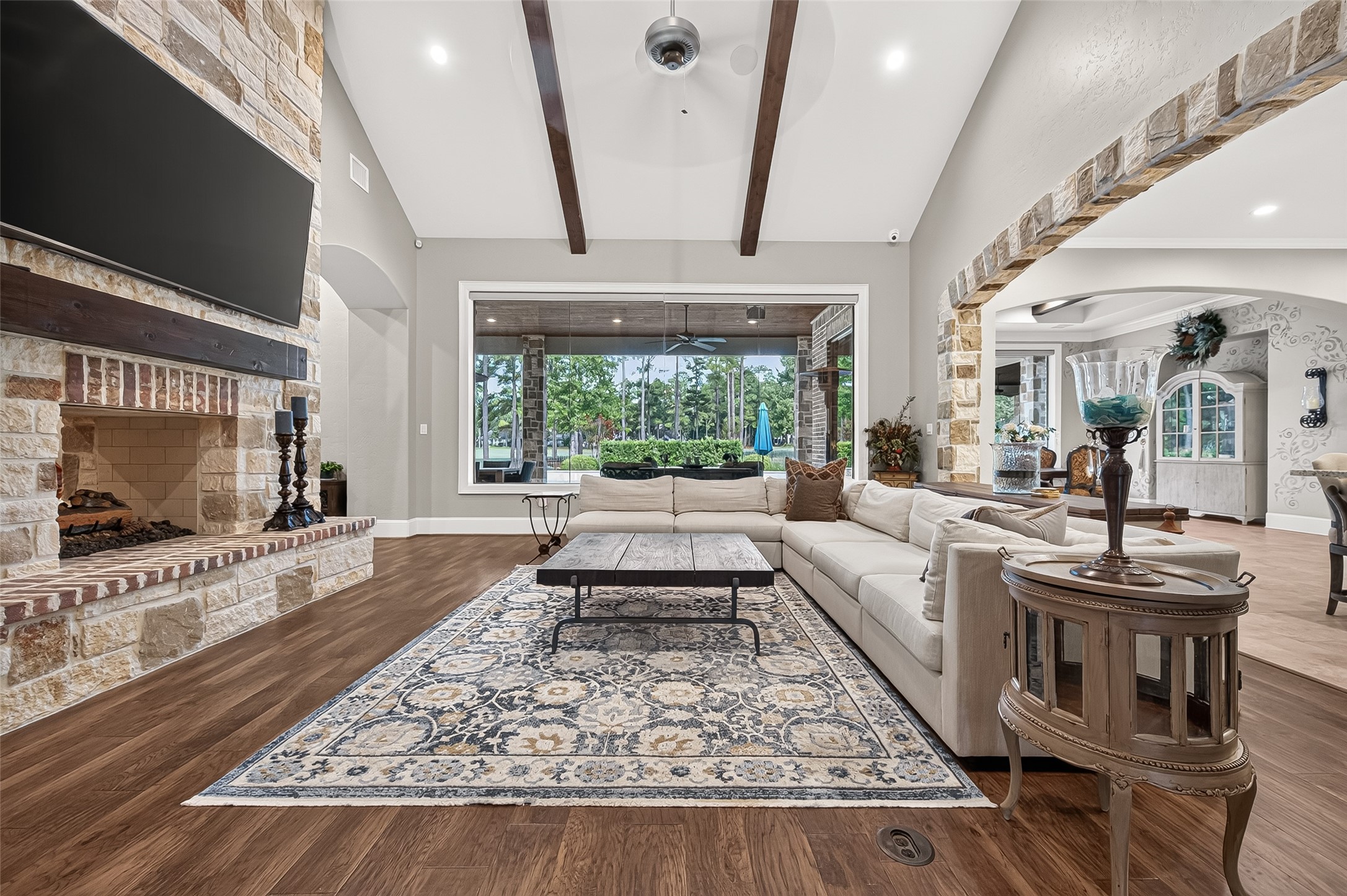 Family room with a vaulted, beamed ceiling and a floor-to-ceiling stone fireplace, plus oversized picture window looking out to the covered patio and pool area. Family room with a vaulted, beamed ceiling and a floor-to-ceiling stone fireplace, plus oversized picture window looking out to the covered patio and pool area.