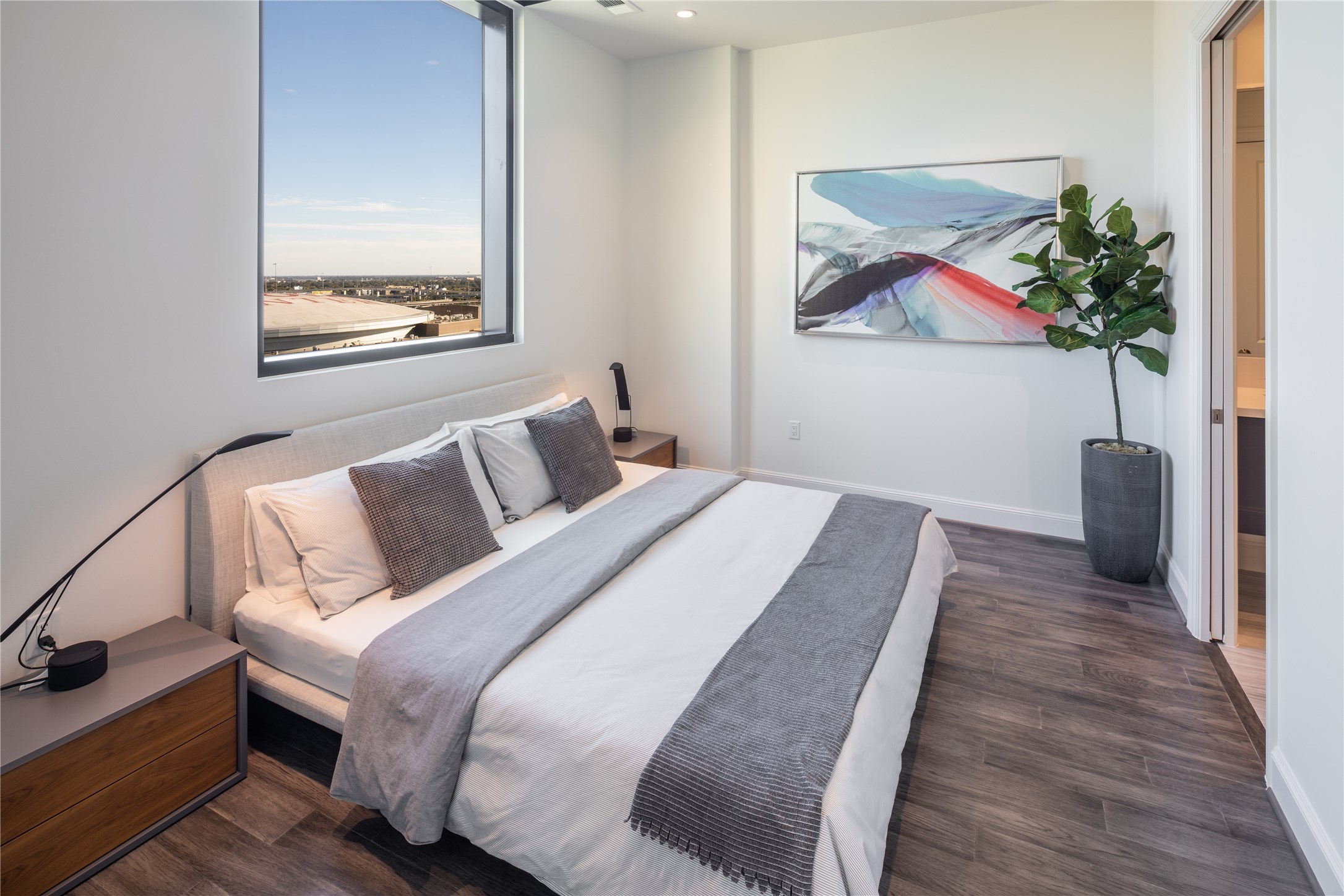 [Primary Bedroom VIRTUALLY STAGED]  Primary bedroom boasting elegant hardwoods and picture window, suitable for king size bed