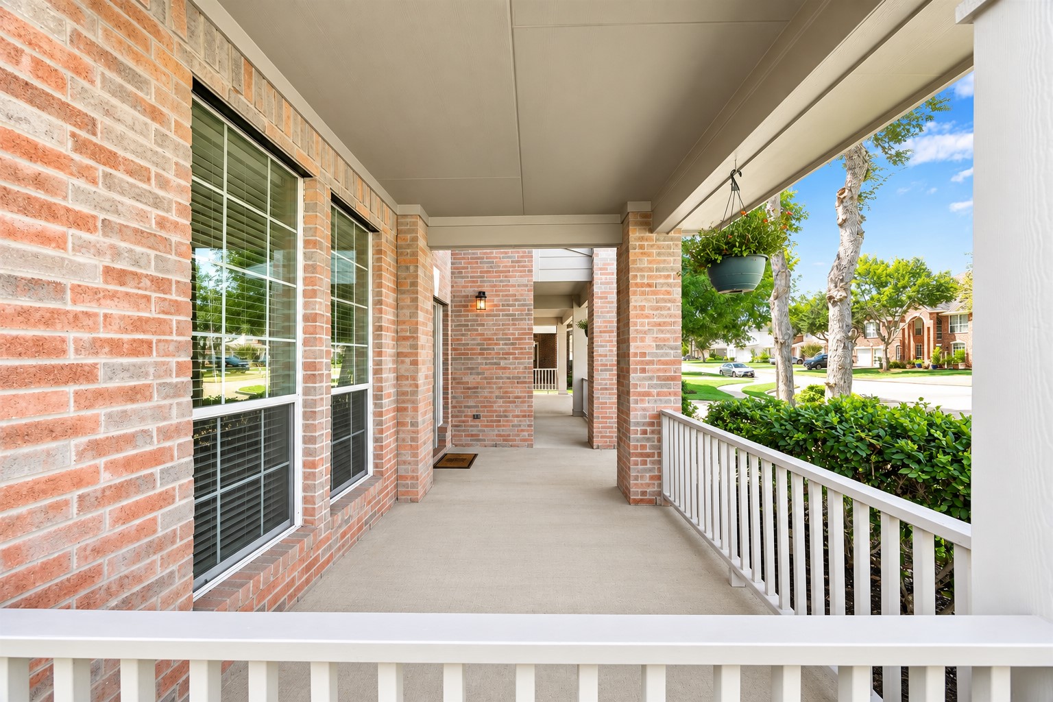 EXPANSIVE COVERED FRONT PORCH WITH BRICK COLUMNS AND PLENTY OF SPACE TO CREATE A WELCOMING OUTDOOR SITTING AREA.