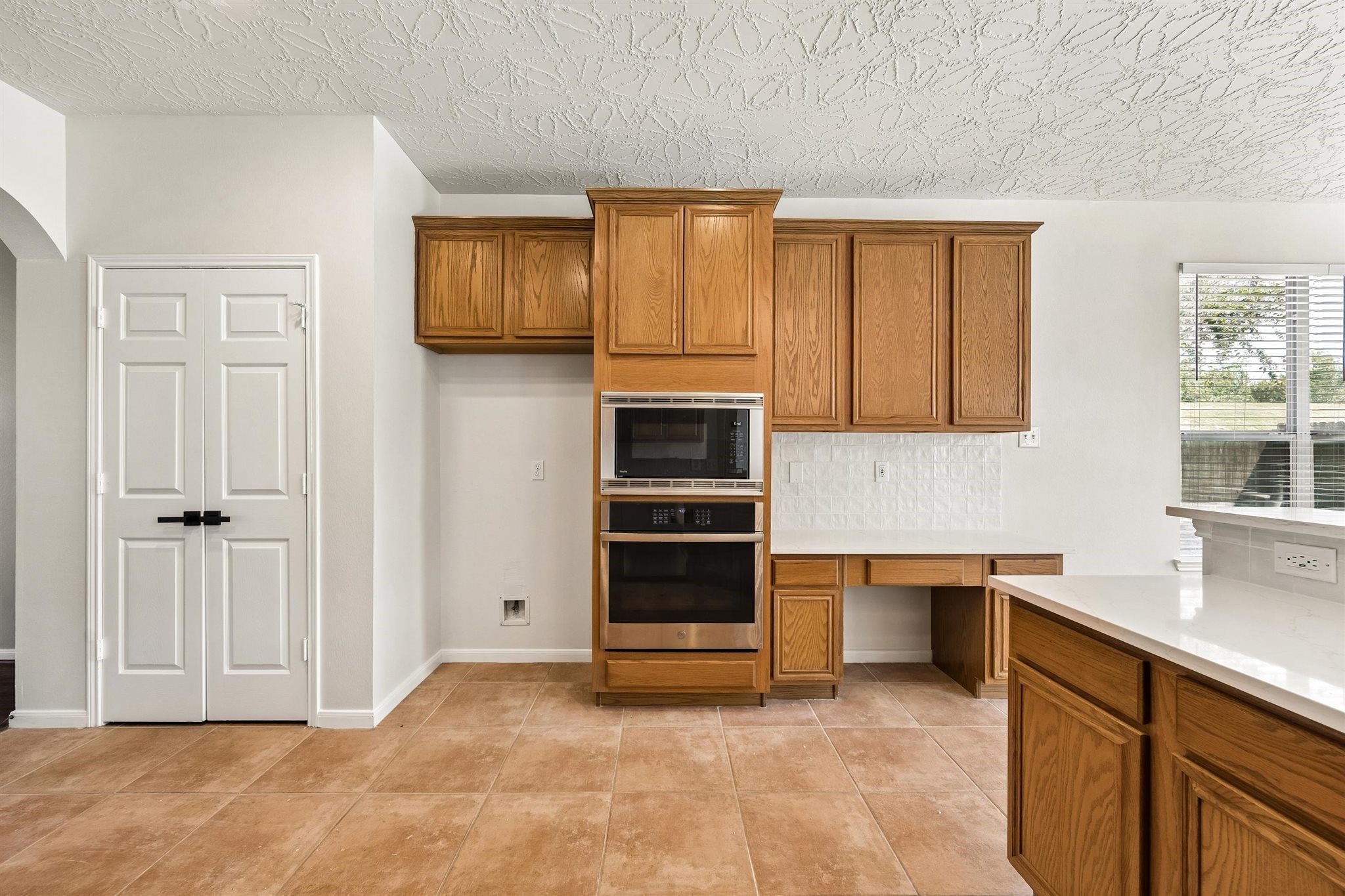 WELL-APPOINTED KITCHEN FEATURING WHITE COUNTERTOPS, STAINLESS STEEL APPLIANCES, A GAS COOKTOP, AND ABUNDANT CABINET STORAGE.