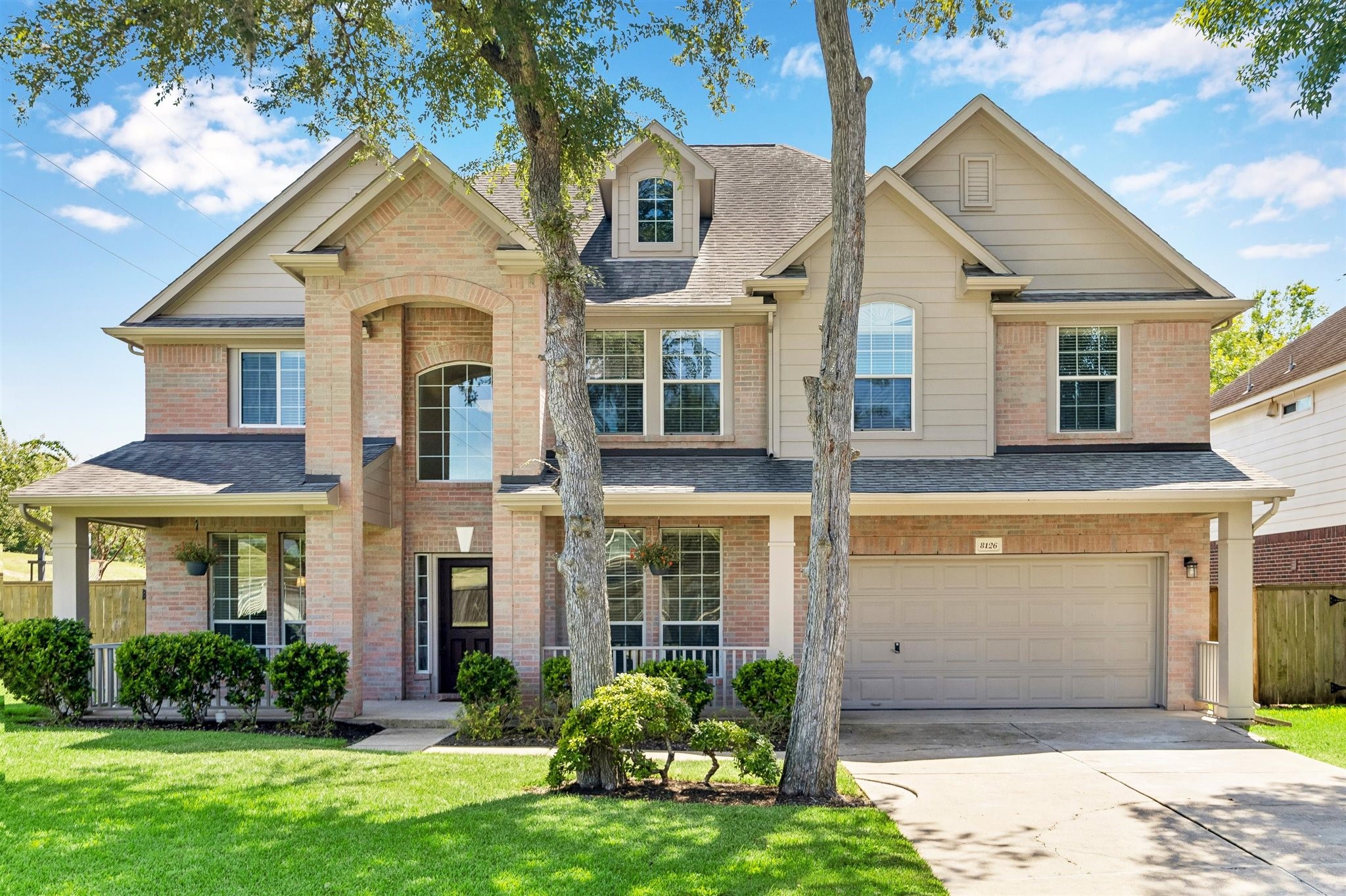 IMPRESSIVE TWO-STORY ELEVATION WITH CLASSIC BRICK DETAILING, MATURE SHADE TREES, AND A WELCOMING COVERED FRONT PORCH.
