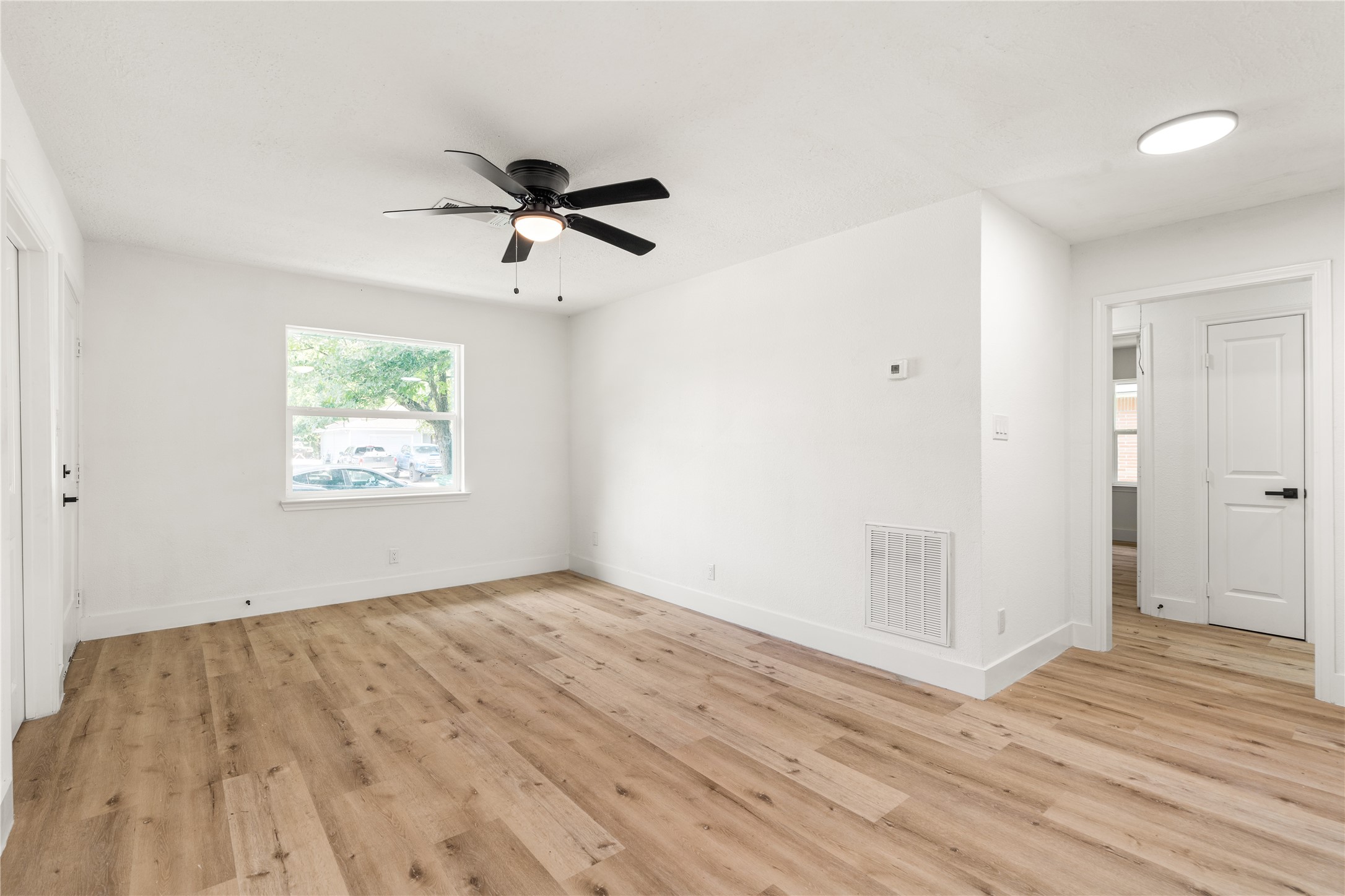 Another angle of living area featuring the crisp white walls, and a modern ceiling fan. Another angle of living area featuring the crisp white walls, and a modern ceiling fan.