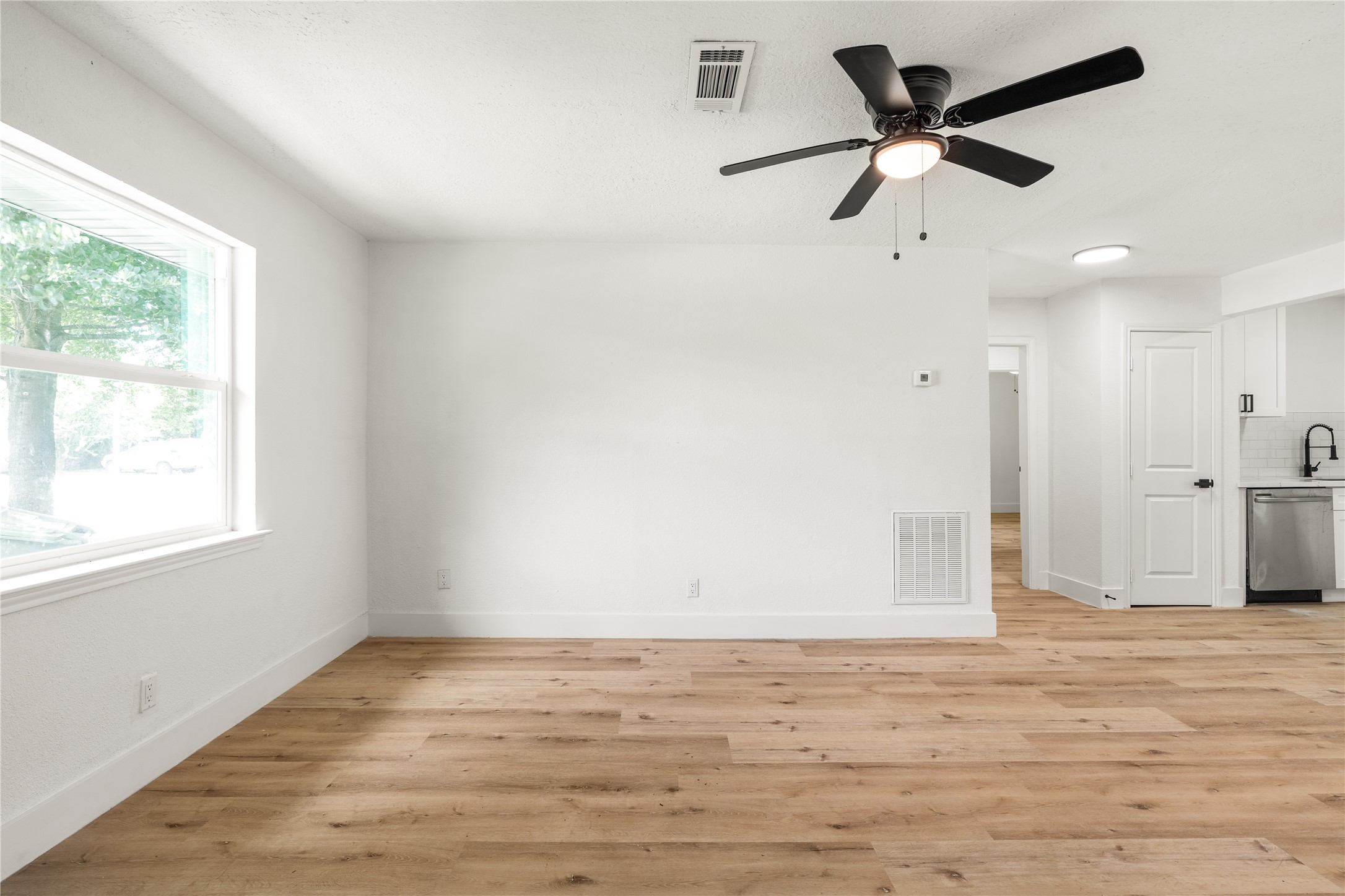 Expansive living space featuring rich wood-look flooring and continuous flow into the adjacent kitchen. Expansive living space featuring rich wood-look flooring and continuous flow into the adjacent kitchen.