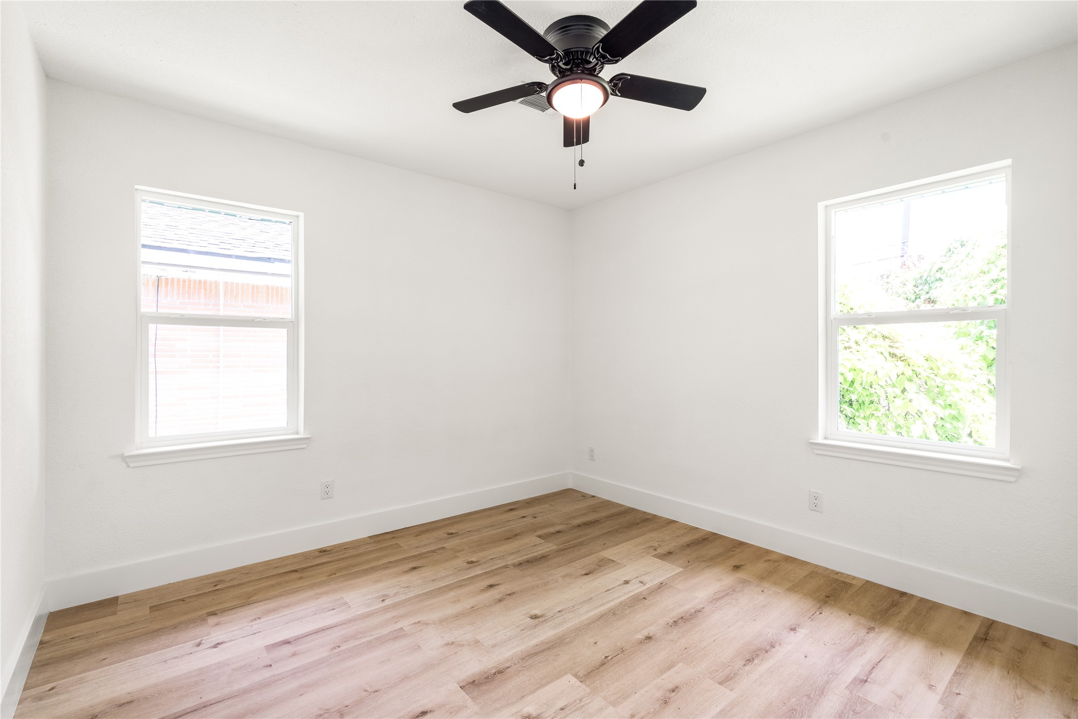 Sunlit bedroom with beautiful light wood flooring, fresh neutral finishes, and great natural light.