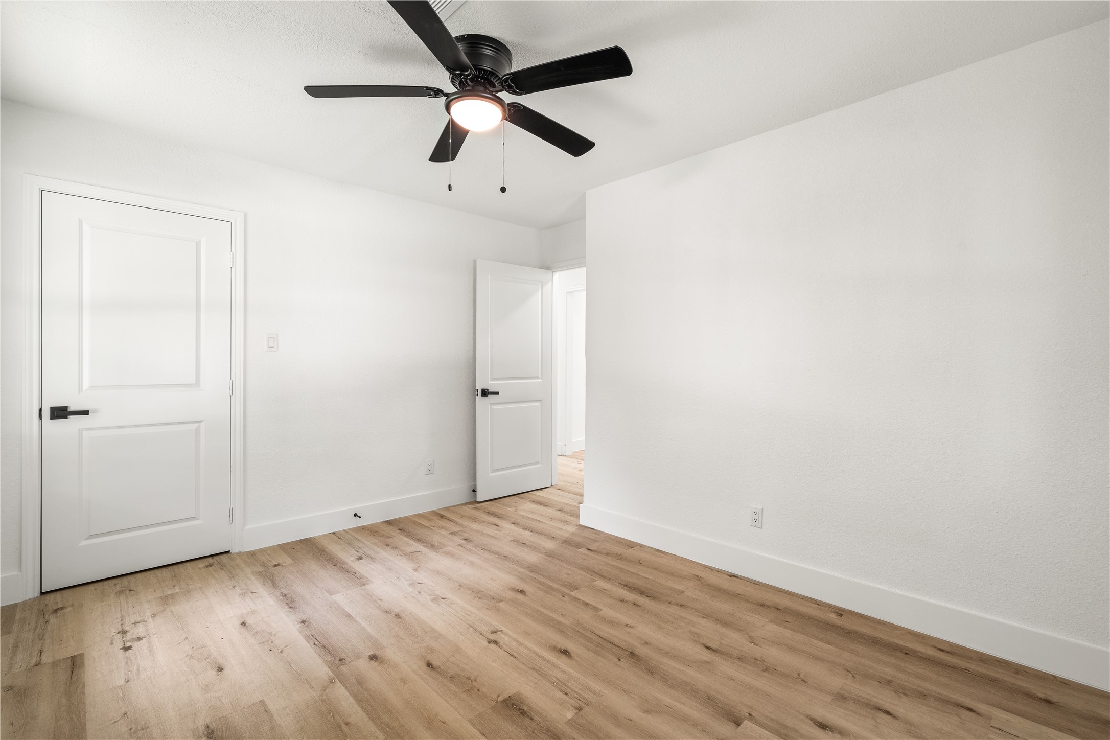 Reverse view of Bedroom highlighting beautiful wood-look flooring, crisp white trim, and modern door hardware.