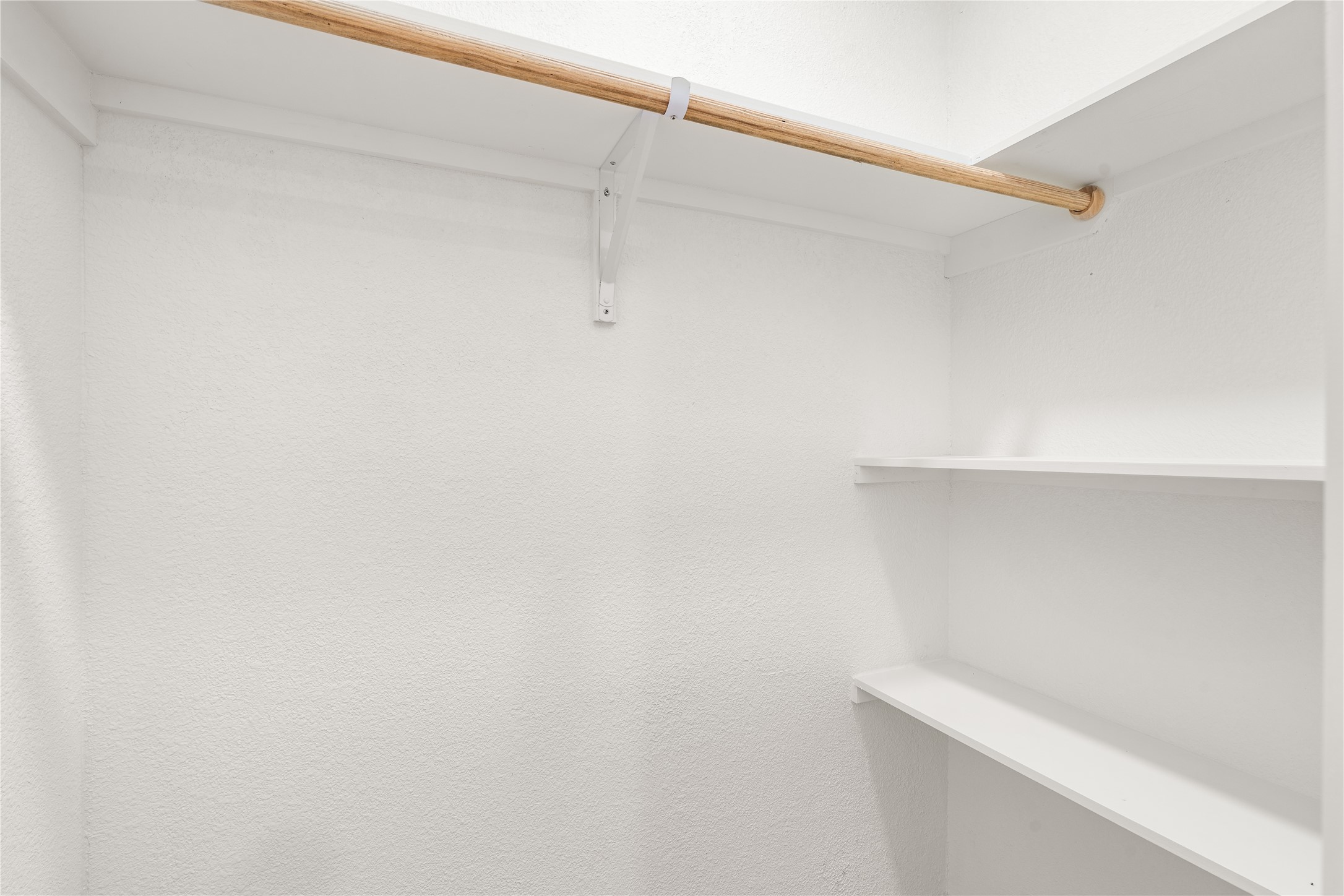 Thoughtfully designed walk-in primary closet with generous storage, open shelving, and ample hanging space for effortless organization.