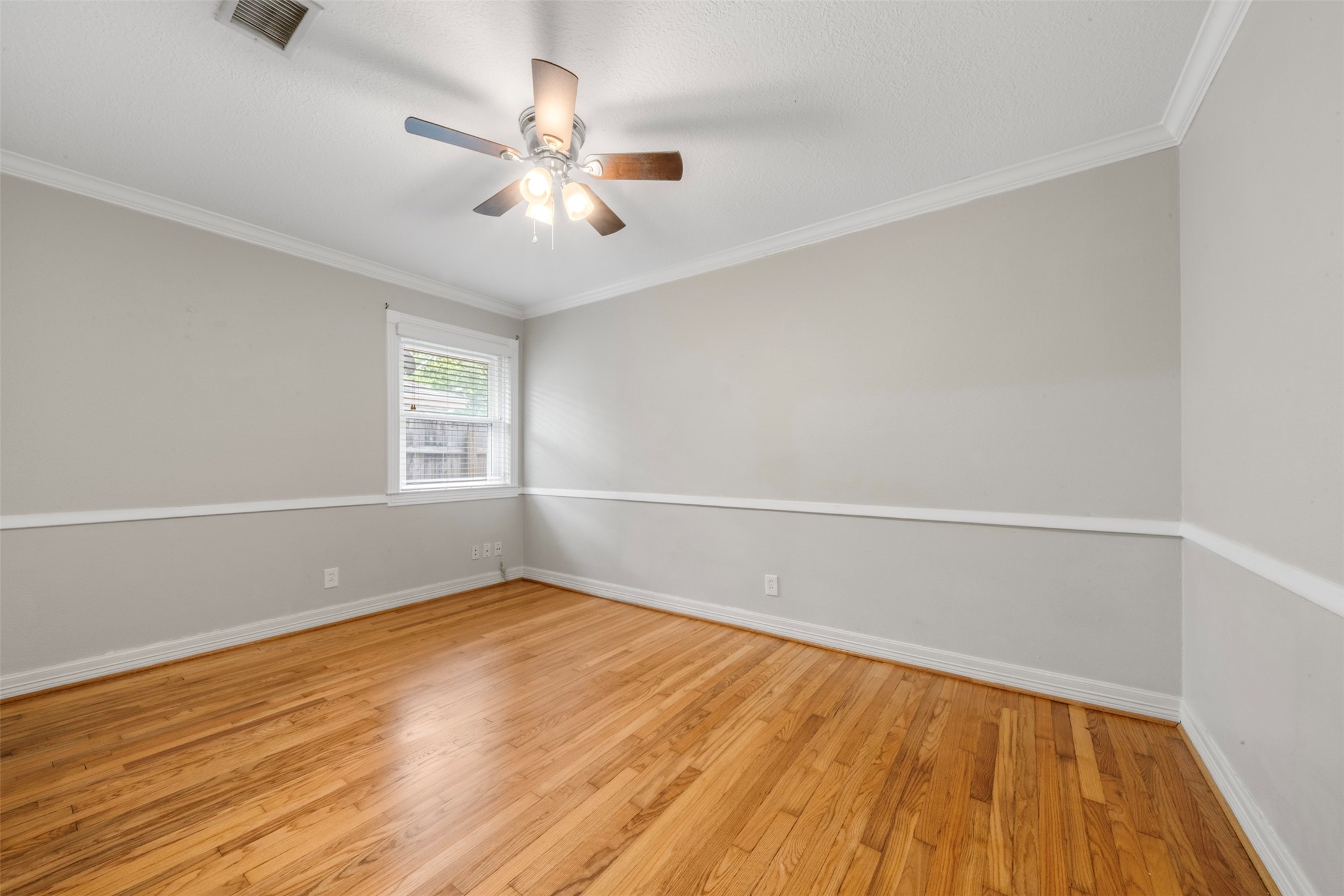 Bedroom 1 with polished wood floors, fresh paint and chair rail.