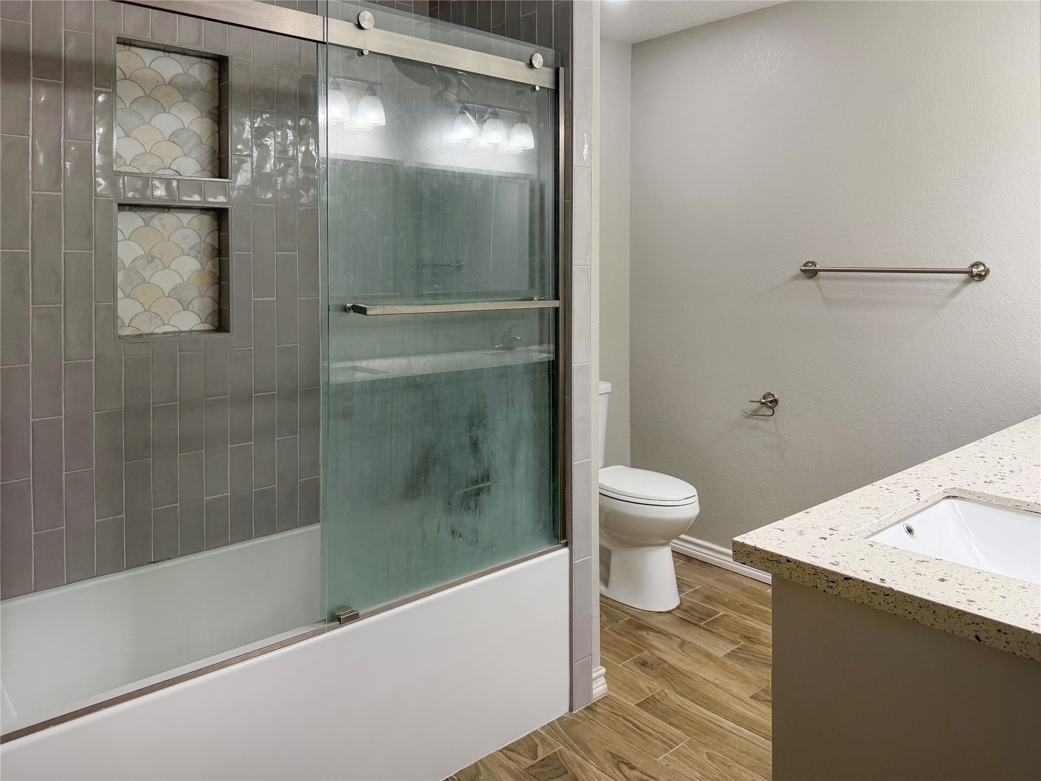 Primary bathroom features a tub and shower combination with a glass door, offering a clean, functional space for everyday use.