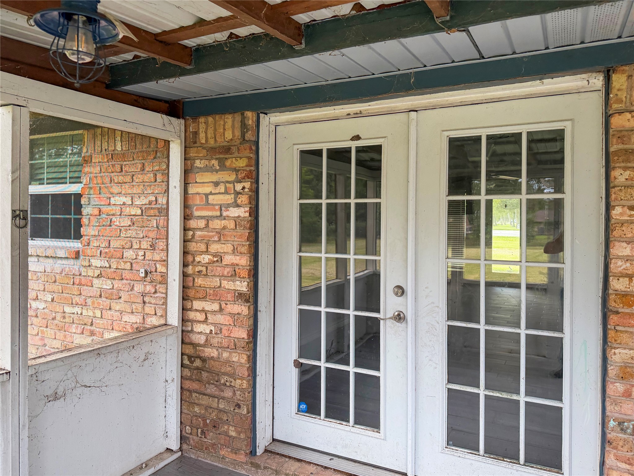 Small screened-in back porch features double doors leading into the home, offering a comfortable space to relax and enjoy the outdoors.