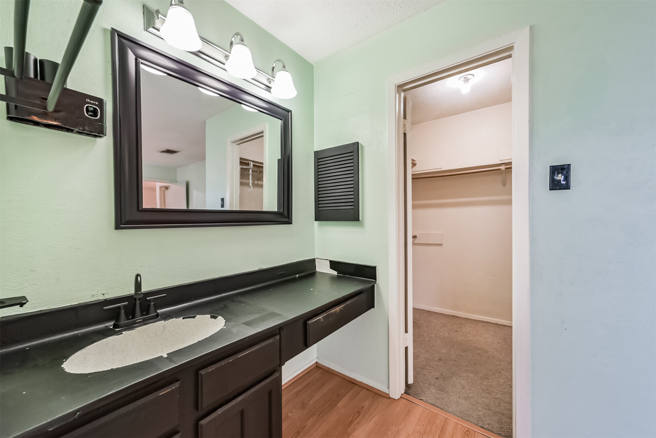 Modern bathroom with a sleek black countertop, stylish mirror, and ample cabinet space, leading to a spacious walk-in closet.
