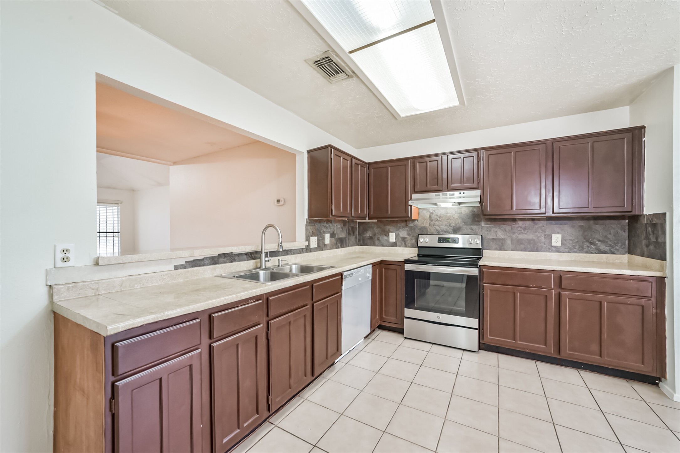 Spacious kitchen with rich wood cabinetry, sleek stainless steel appliances, and ample counter space, perfect for culinary enthusiasts.