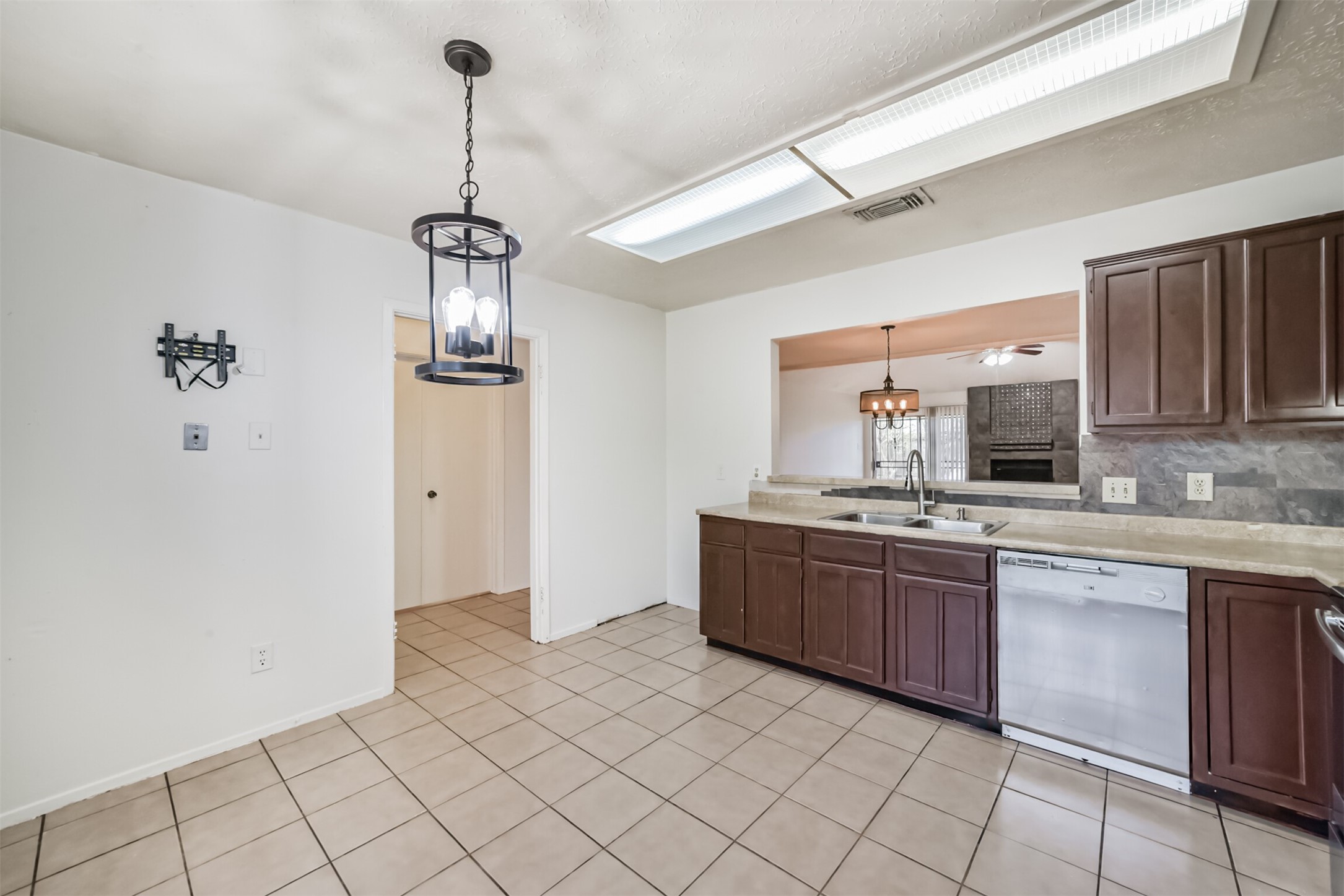 Spacious kitchen featuring dark wood cabinetry, modern light fixtures, and a convenient pass-through window to the living area.