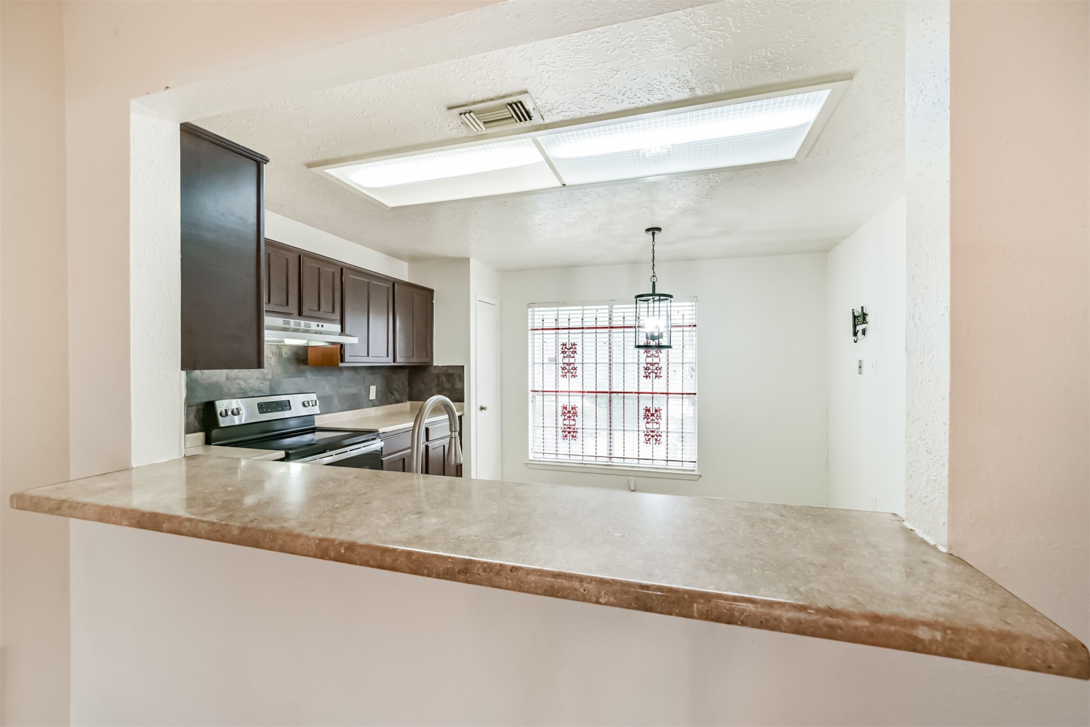 Bright kitchen with dark cabinetry, modern appliances, and a cozy dining nook featuring a unique stained glass window.