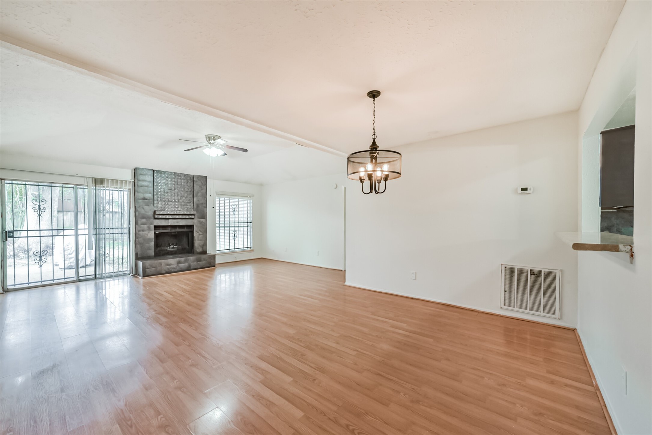 Spacious living area with elegant hardwood floors, a cozy fireplace, and abundant natural light from large windows and a sliding door.