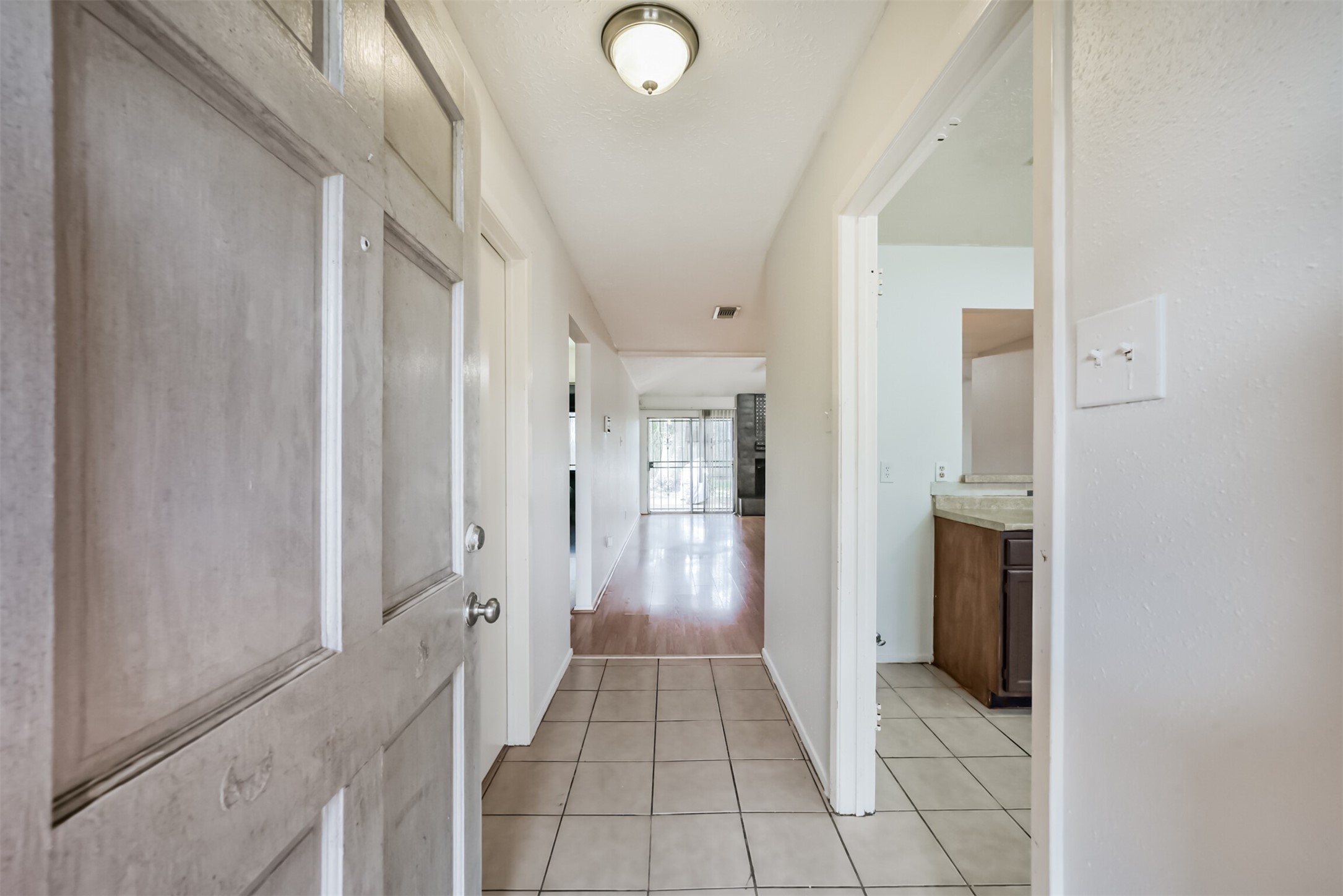 Inviting entryway with tile flooring leads to a bright, open hallway, seamlessly connecting to the living area and kitchen.