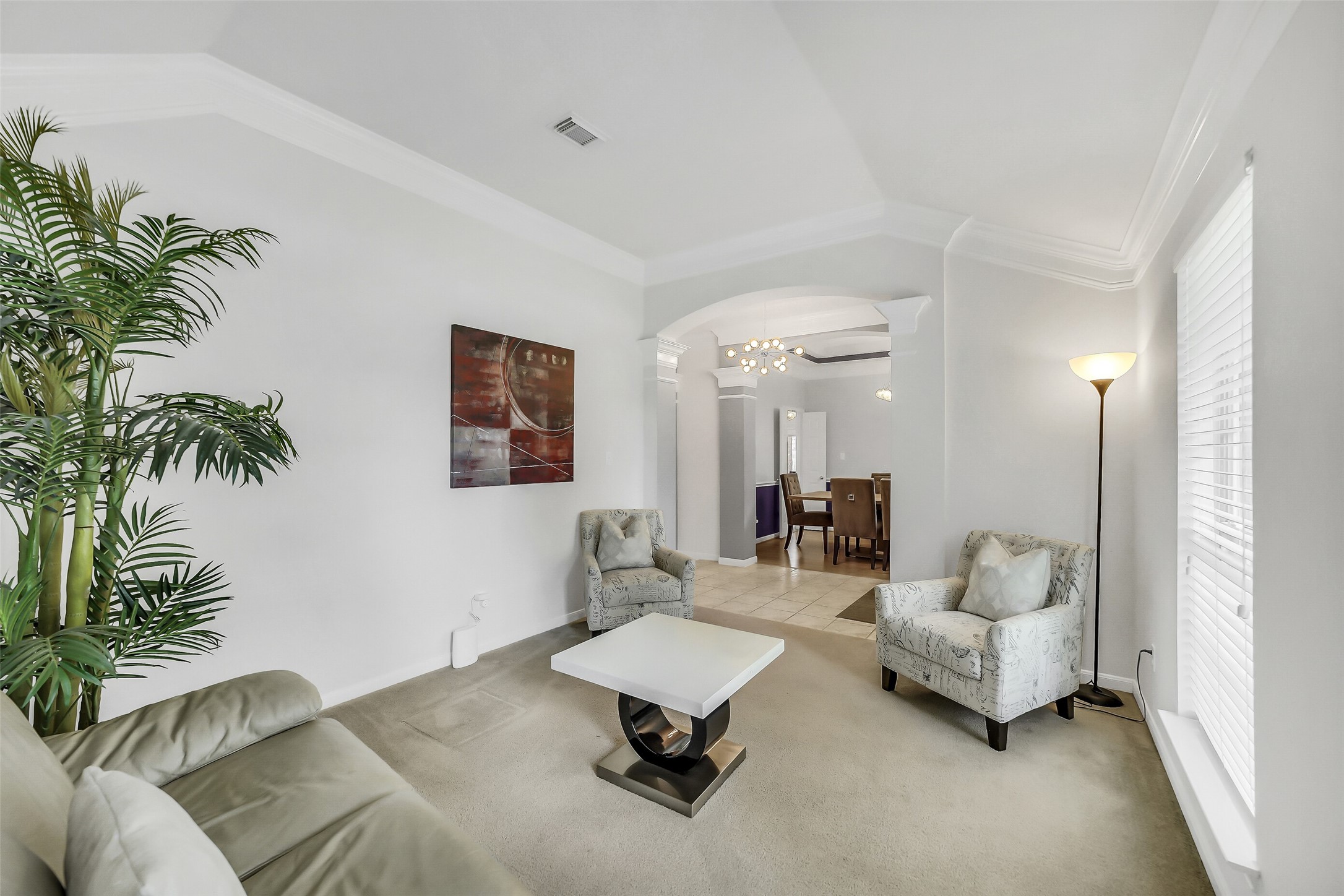 The elegant formal living room has abundant natural light, and an inviting archway leading to the dining area.