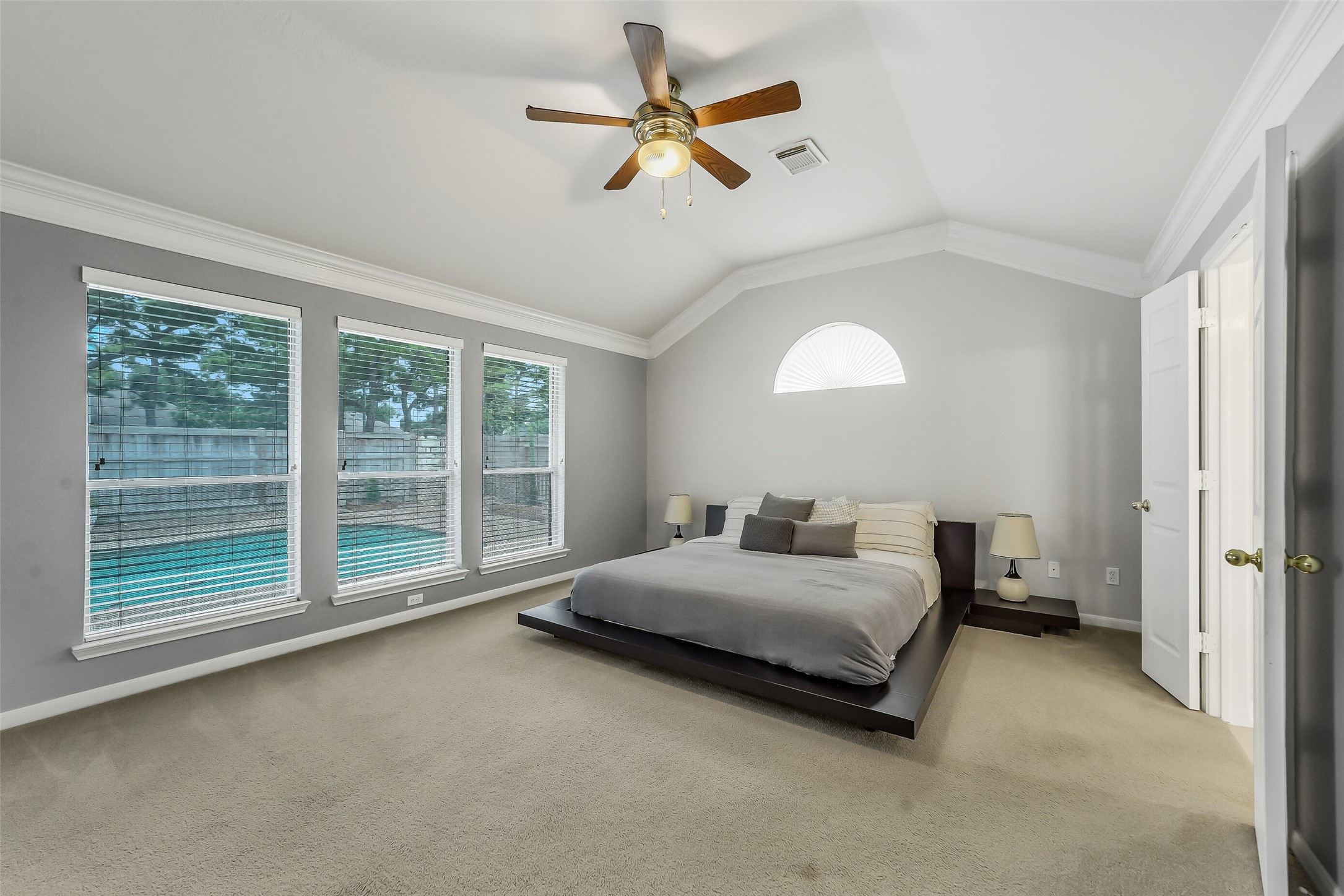 Experience luxury in this spacious primary bedroom, offering stunning views of the pool.