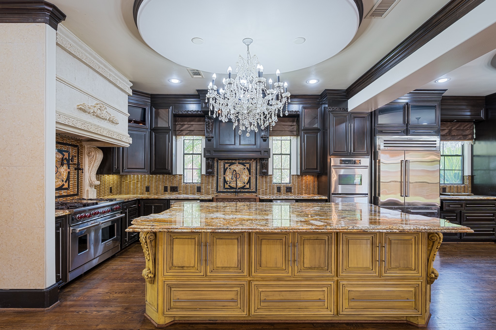 Luxurious kitchen featuring a grand island, custom solid wood cabinetry, and a stunning chandelier, complemented by high-end appliances and elegant details.