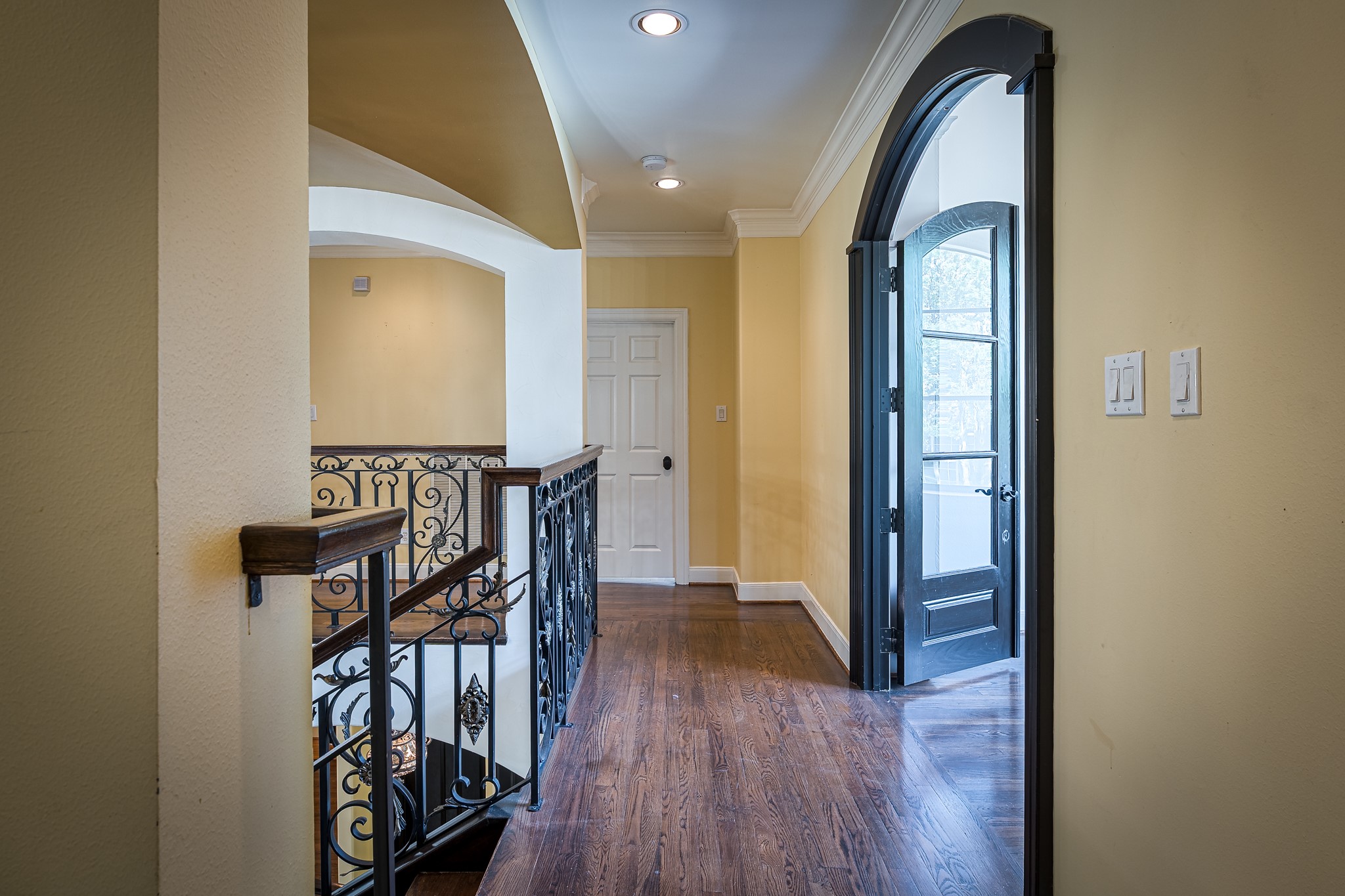 The second floor landing presented with a sunroom style space that is framed with large solid wrought-iron doors.
