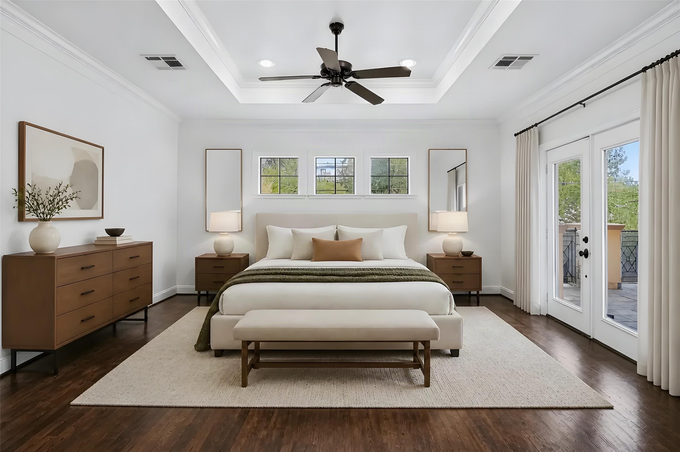 Experience luxury in this spacious bedroom featuring a tray ceiling, elegant hardwood floors, and abundant natural light through French doors leading to a private balcony. *Photo is virtually staged*