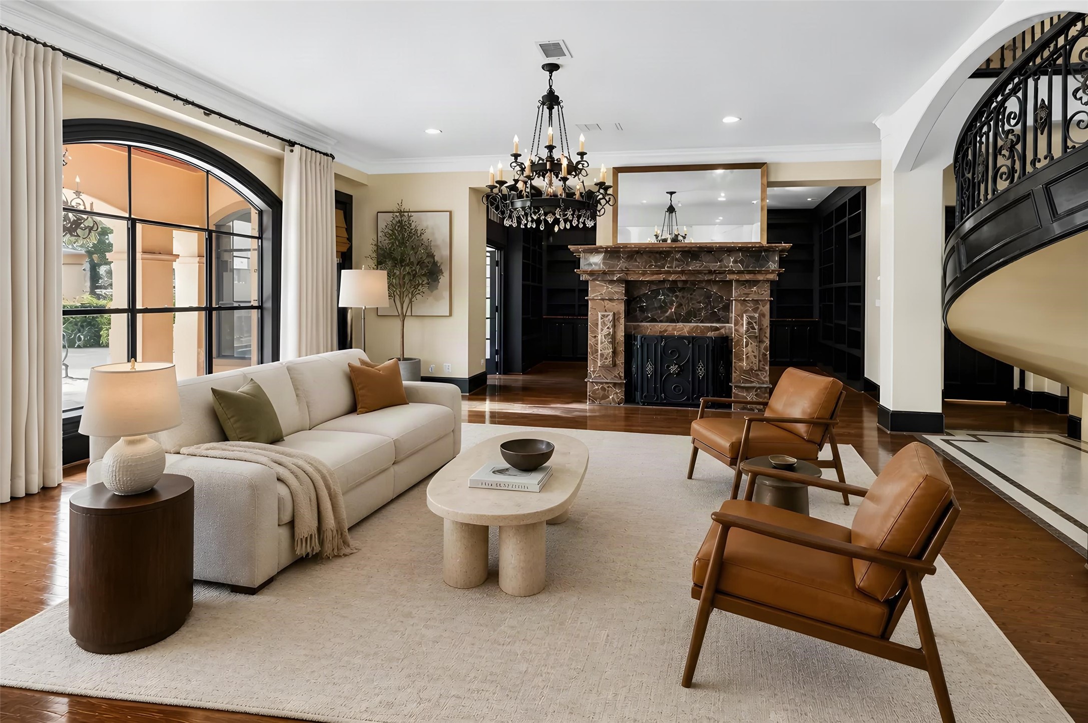 Elegant living room featuring a grand marble fireplace, luxurious chandelier, and a stylish mix of contemporary and classic furnishings. *Photo is virtually staged*