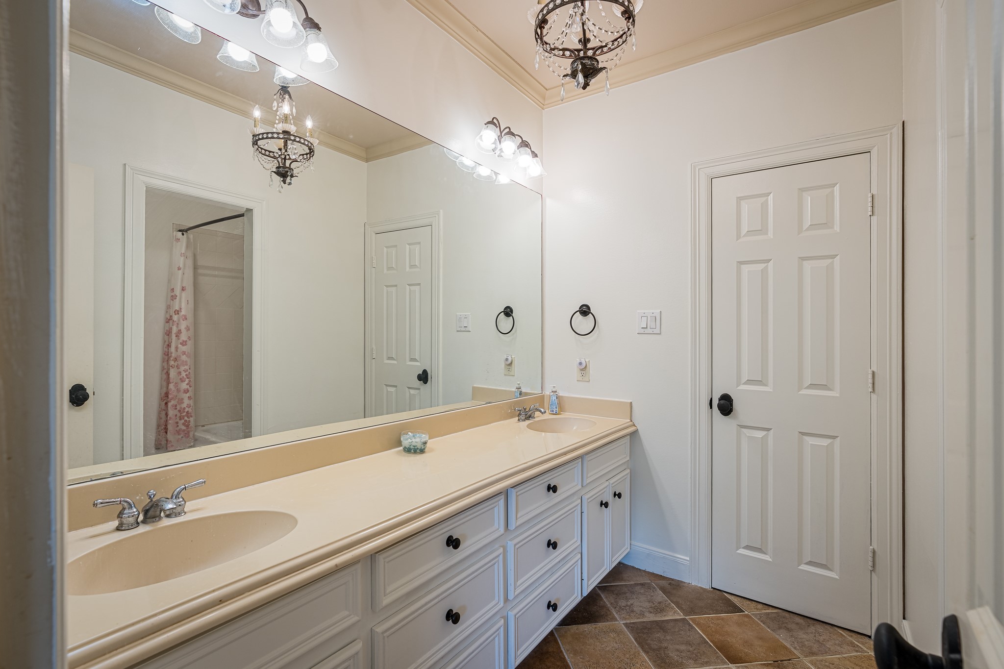 Elegant bathroom featuring a spacious double vanity with ample storage, stylish lighting fixtures, and a chic tile floor, offering both functionality and charm.
