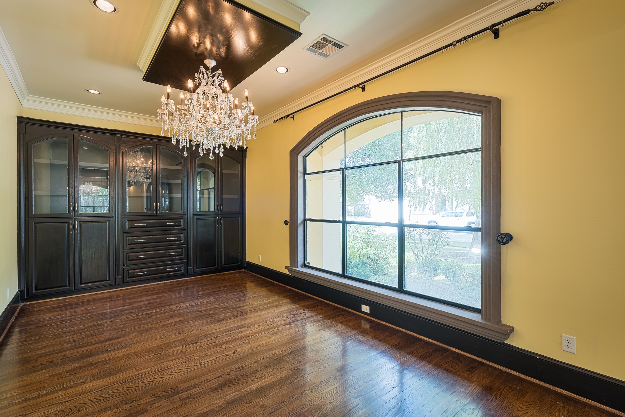Opposite the dining room is a formal living space with a matching chandelier and custom built-in cabinetry.
