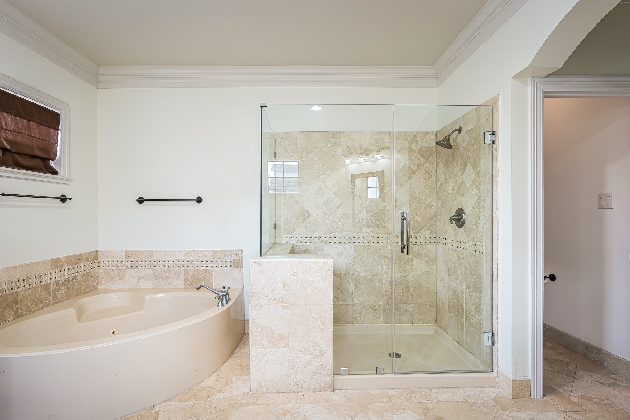 Elegant bathroom featuring a luxurious corner bathtub and a spacious glass-enclosed shower, accented with tasteful tilework for a spa-like retreat.