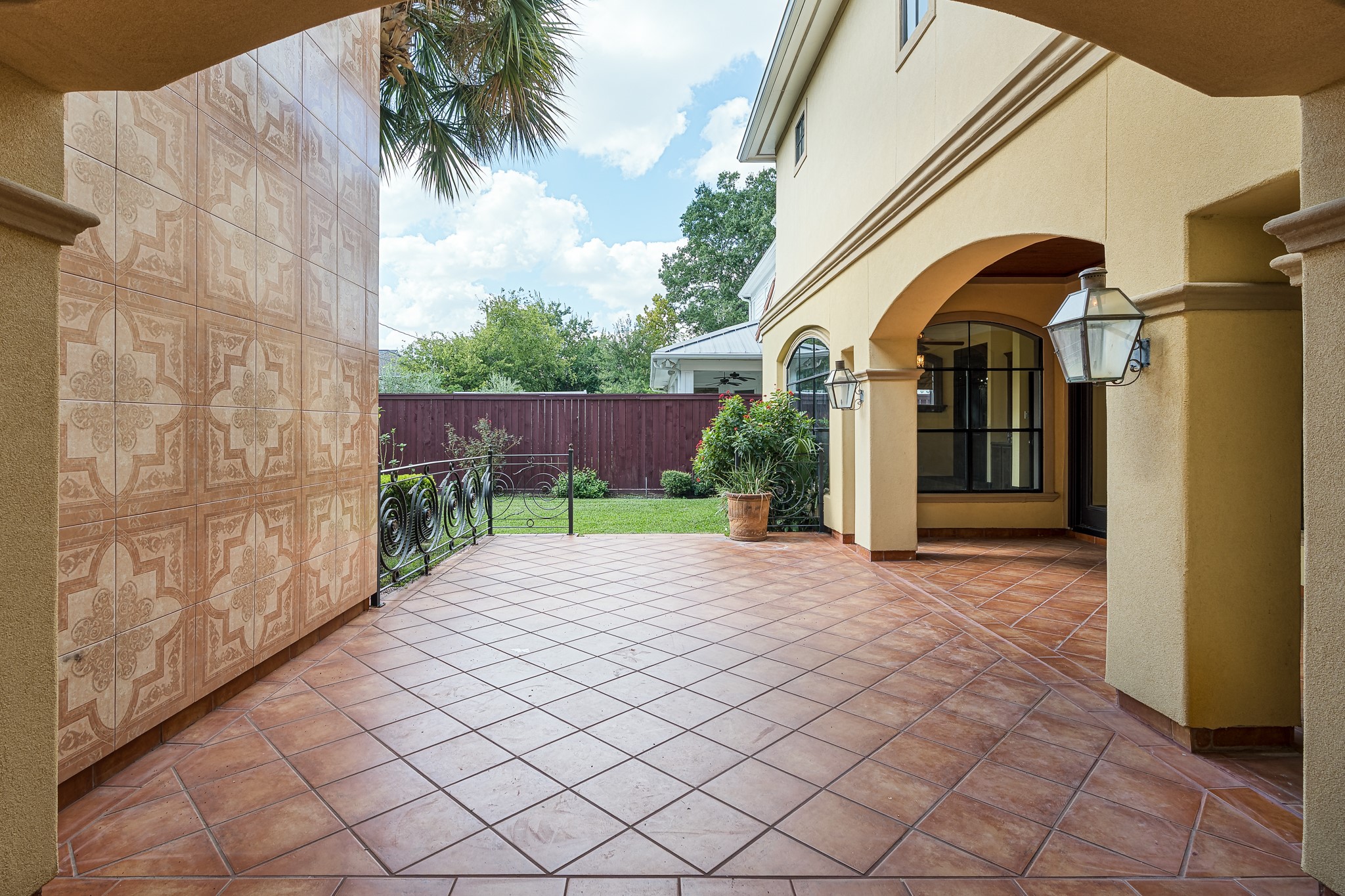 A charming courtyard with elegant tile flooring, decorative wall tiles, and arched entries creates a welcoming outdoor space, perfect for relaxation and entertaining.