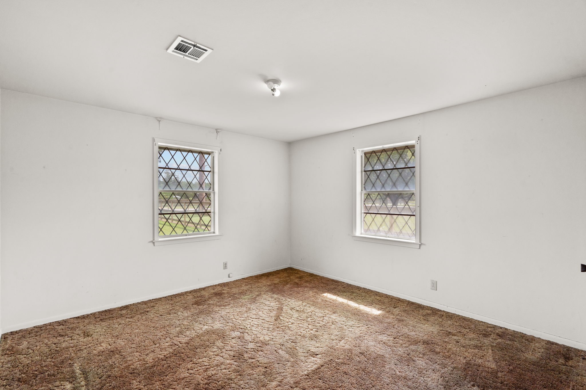 Bedroom with two windows and neutral walls.