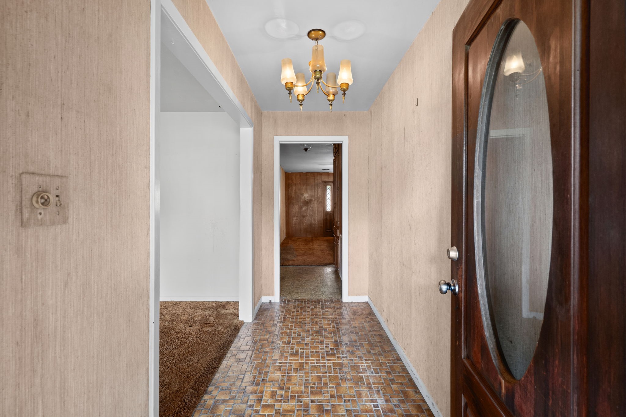 Entryway with brick-pattern flooring and chandelier lighting. Entryway with brick-pattern flooring and chandelier lighting.