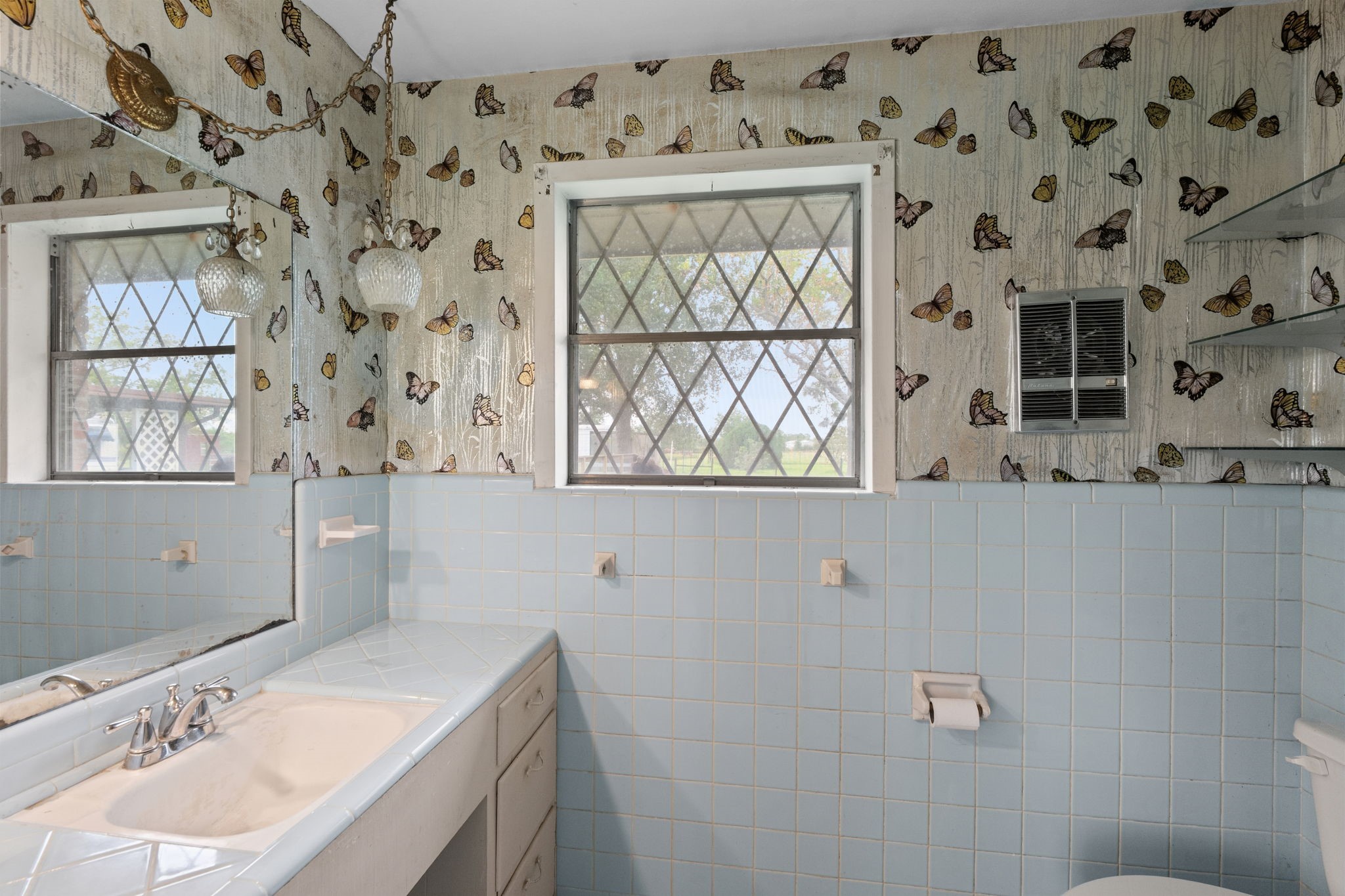 Bathroom with blue tile accents, vanity, and natural light.