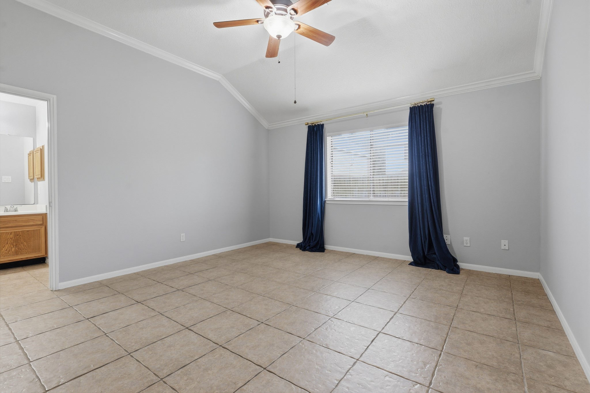 Spacious primary suite with tile flooring, ceiling fan and plenty of natural light.