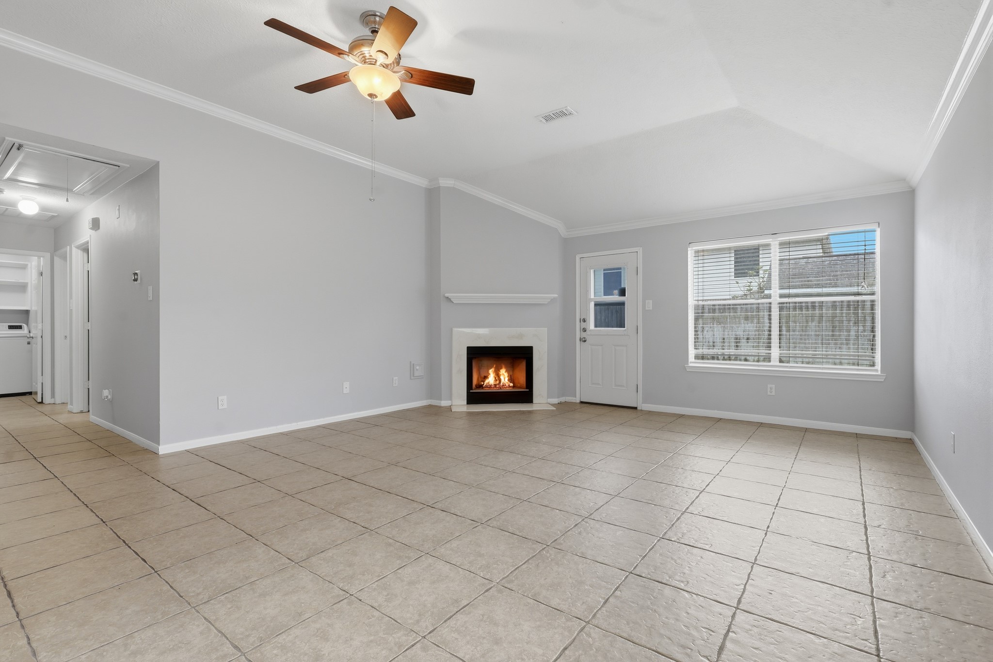 Open-concept living space featuring a cozy fireplace and easy-care tile flooring.