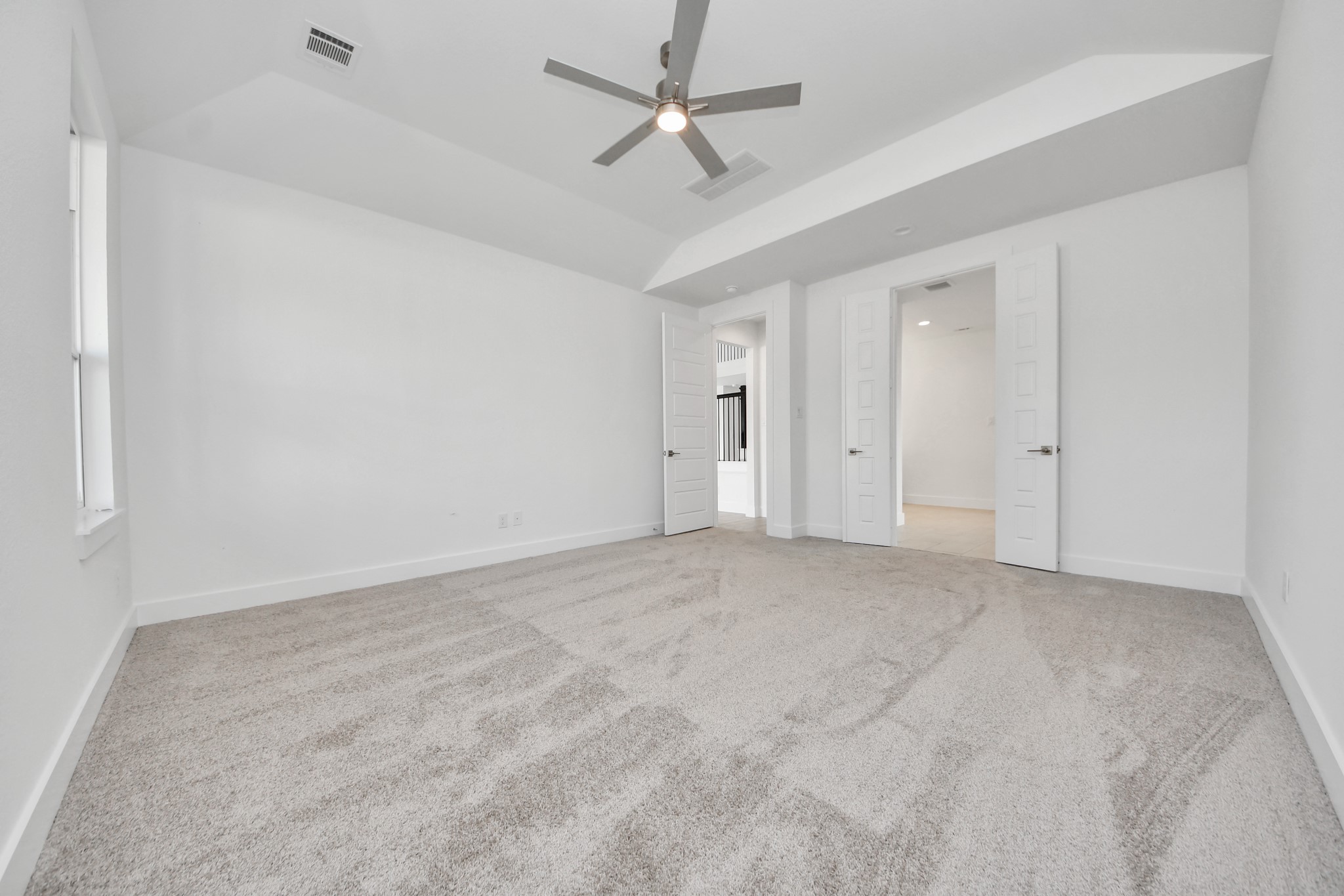 Escape and relax in the exquisite primary suite, a haven to unwind after a long day. The spacious room, located on first floor, boasts plush carpeting, soothing paint tones, high ceilings, and expansive windows adorned with privacy blinds.