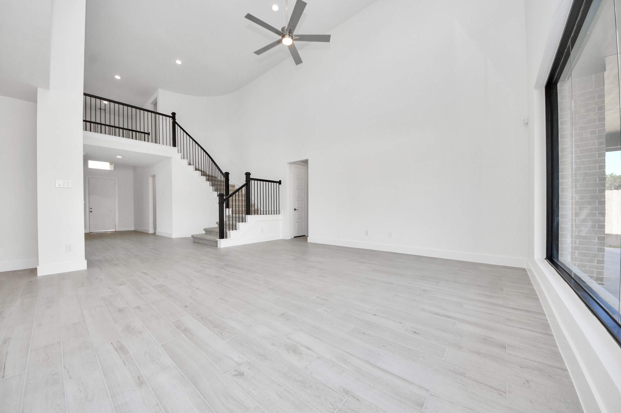 Welcome family and guests to your charming living room! With its high ceilings, recessed lighting, ceiling fan, custom paint, beautiful flooring, and large windows that let in abundant natural light, this room is perfect for gatherings.