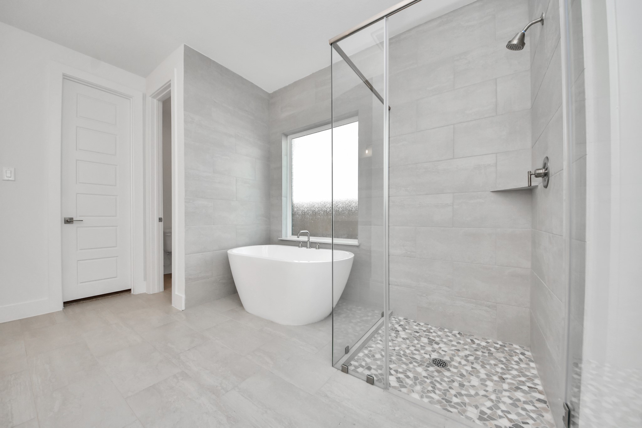 Escape to a spa-like oasis in this primary bathroom. Enjoy a walk-in shower with tile surround, a separate garden tub with custom detailing, and an elegant vanity featuring light countertops, modern hardware, and beautiful vanity lights. Experience luxury and relaxation in every detail.