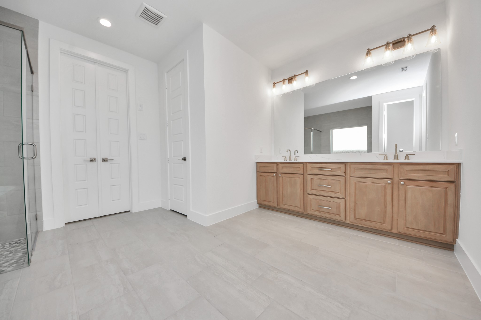 Elevate your daily routine at the elegant vanity, now equipped with double sinks, light countertops, modern hardware, and beautiful vanity lights.