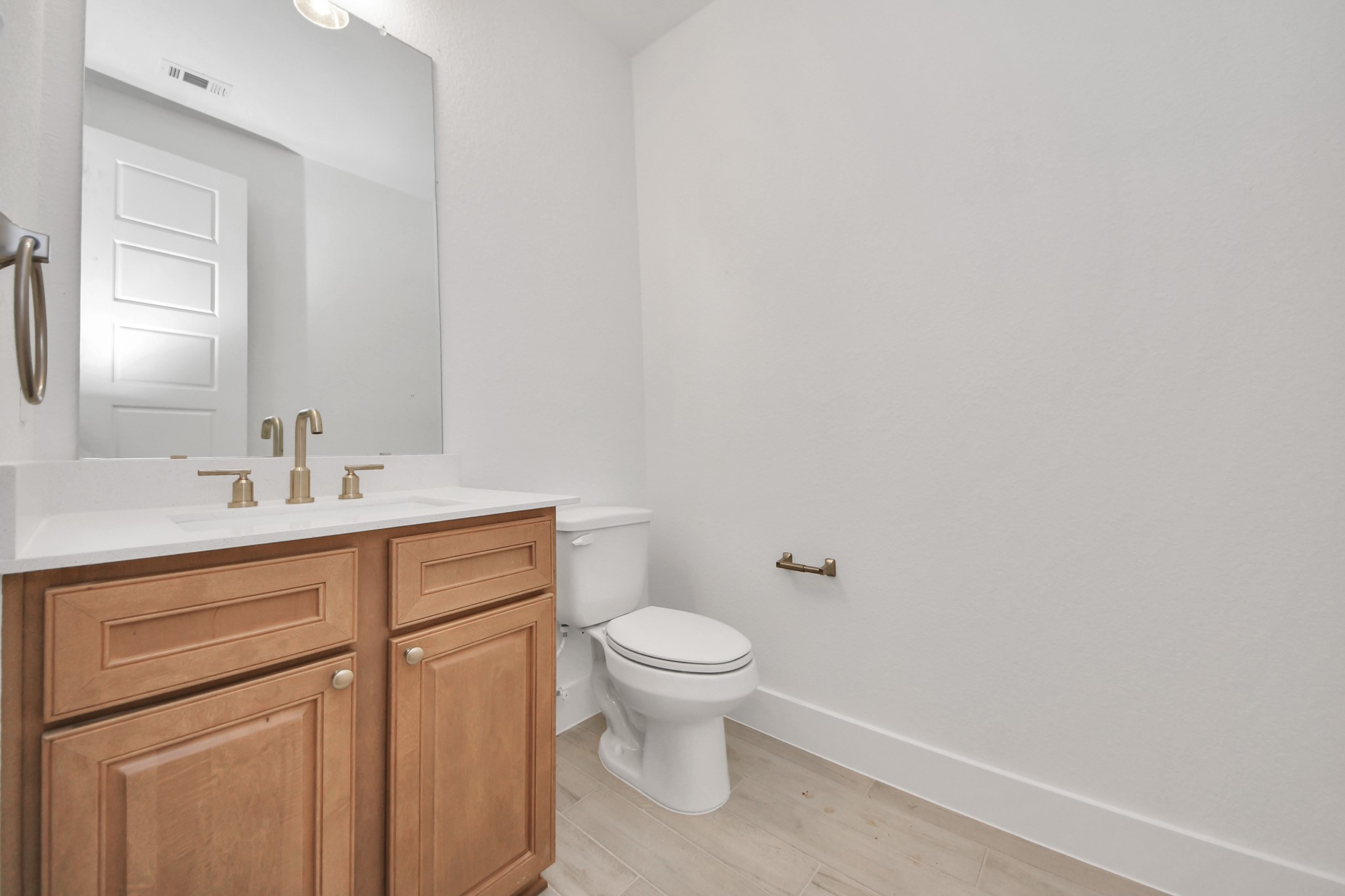 Sophisticated half bathroom adorned with contemporary finishes. The elegant 5-panel door welcomes you to a space where style meets functionality. Notice the sleek hardware accents that add a touch of modern charm. The vanity boasts light-colored countertops, beautifully complemented by a tasteful vanity light, creating a well-lit and inviting atmosphere.