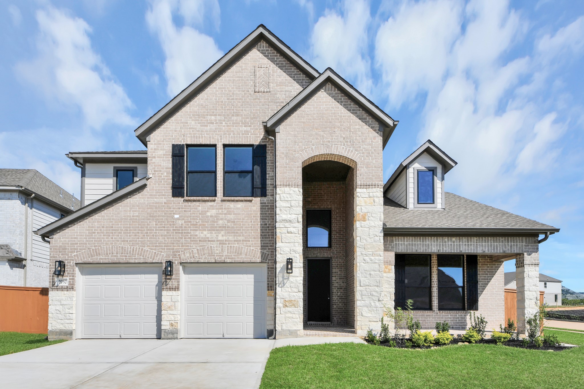 This home boasts lush green grass and meticulous landscaping. Its premium elevation showcases an exquisite blend of brick and stone features, complemented by modern coach lighting