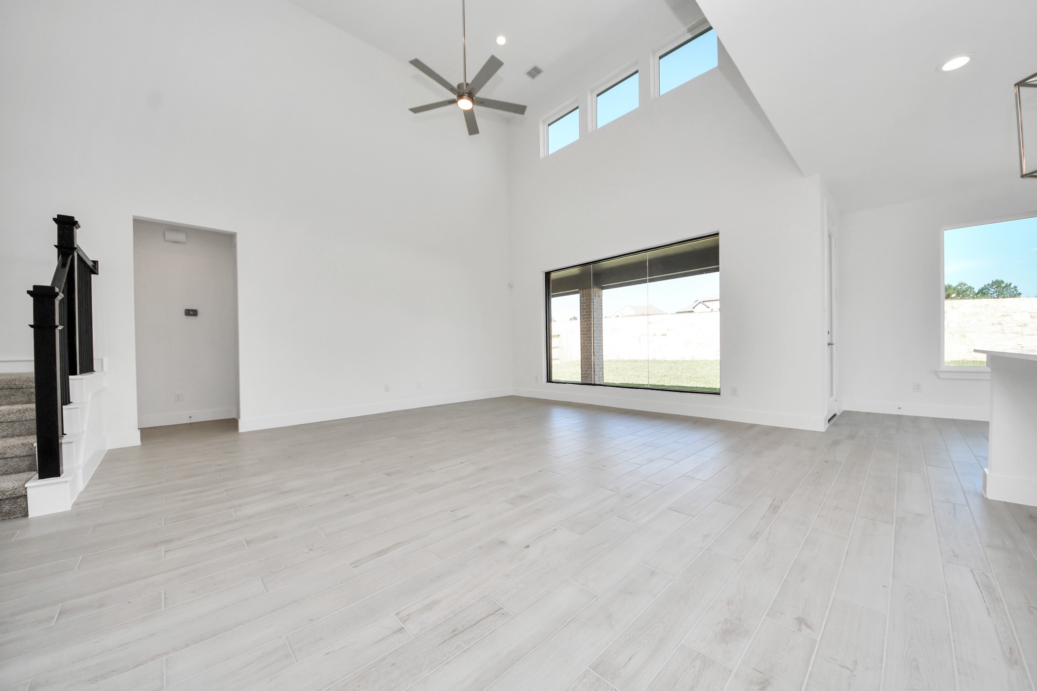 Family room flooded with natural light through the expansive windows.  The premium tile flooring adds a touch of luxury to the space, creating the perfect setting for relaxing moments and cherished gatherings with loved ones