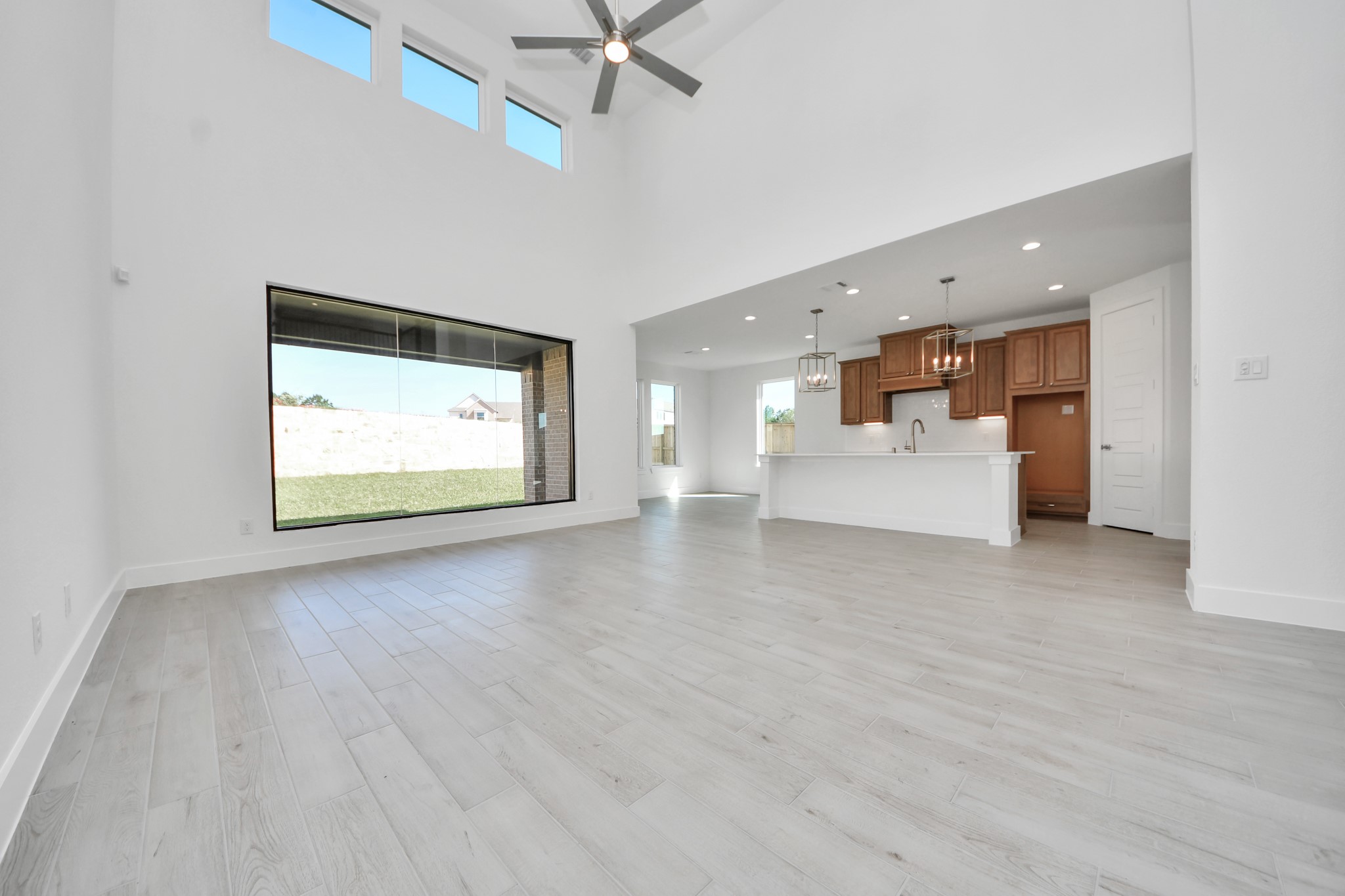 Relax and unwind in this inviting family room, illuminated by abundant natural light streaming in through tall windows, complemented by high ceilings and stunning flooring. Stay comfortable year-round with the gentle breeze from the ceiling fan, creating the perfect atmosphere for family gatherings.