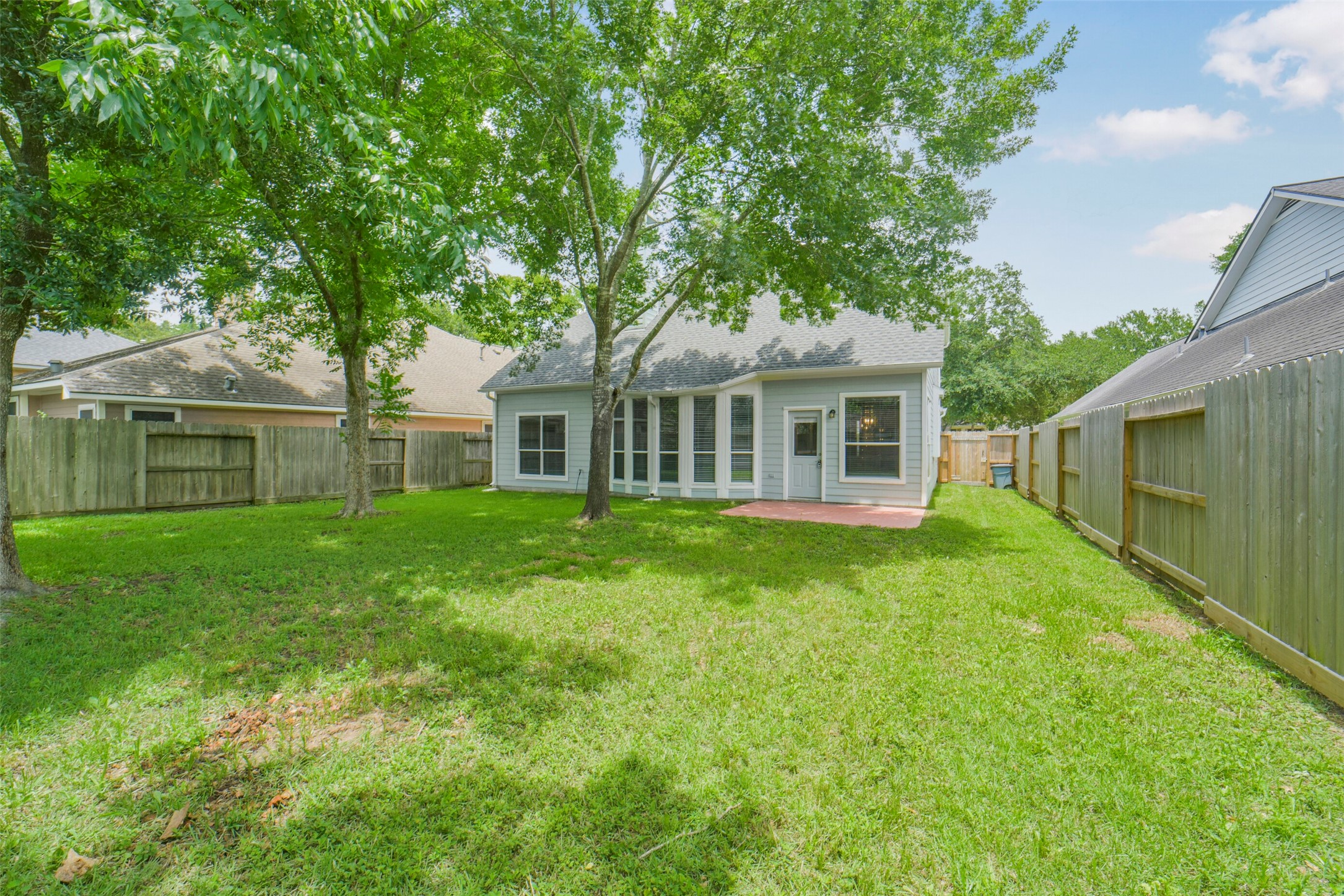 An alternate view of the spacious backyard showcases the lush green lawn and great privacy, perfect for outdoor activities.