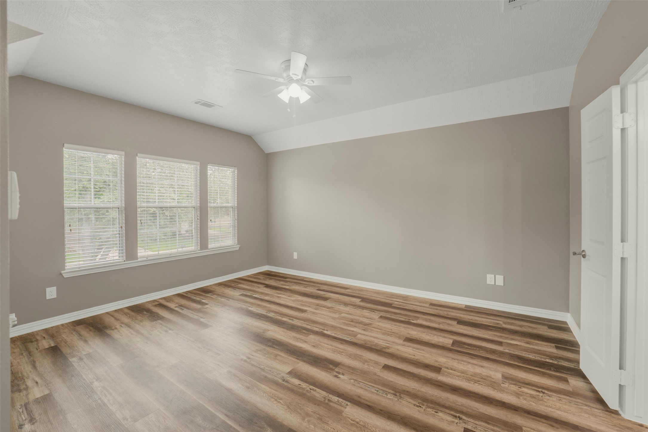 The expansive primary bedroom serves as a peaceful retreat, highlighted by large windows that fill the room with natural light.