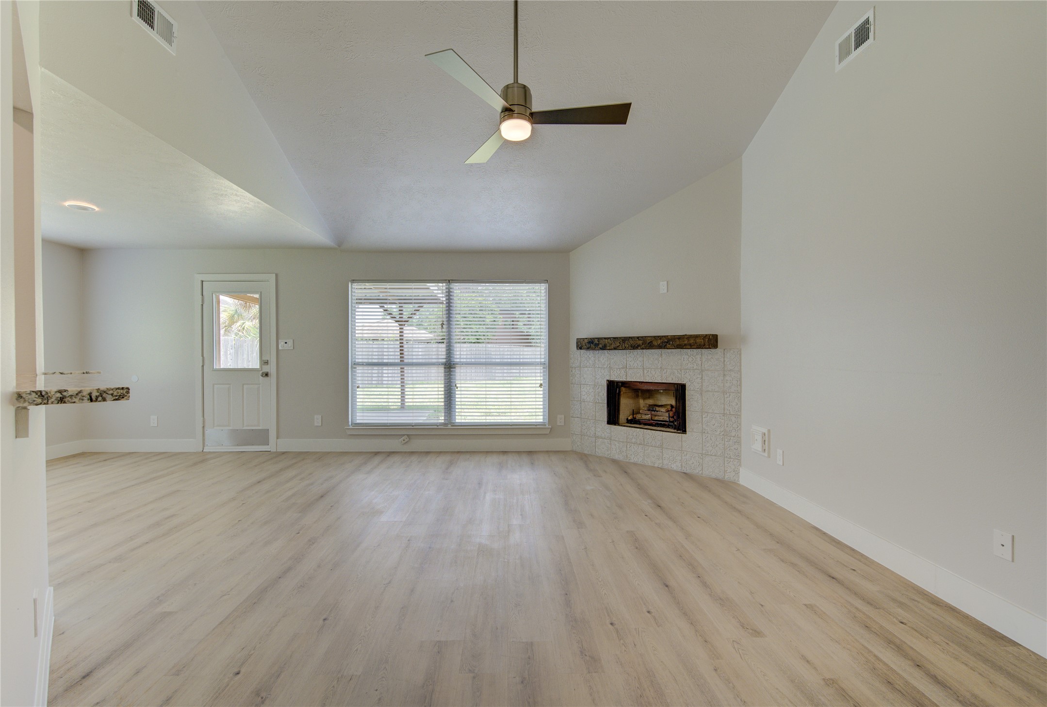 An open airy living space designed for comfortable everyday living, featuring dramatic ceiling height updated flooring and seamless flow to the kitchen and dining areas