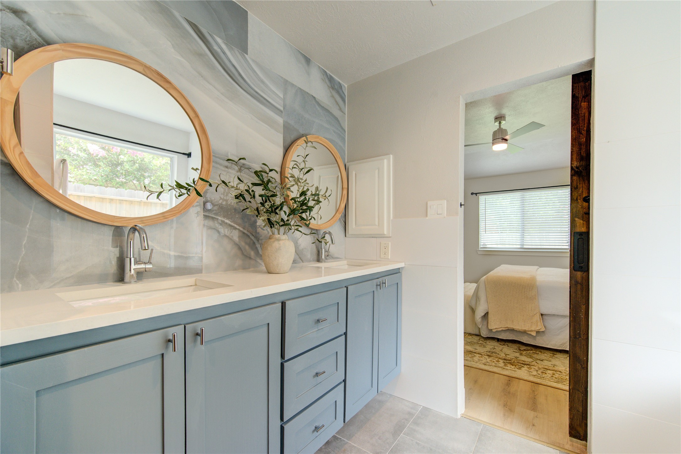 Enjoy a spa-inspired primary bath featuring dual sinks, abundant vanity storage, contemporary fixtures and direct access to the spacious primary suite through a custom barn door