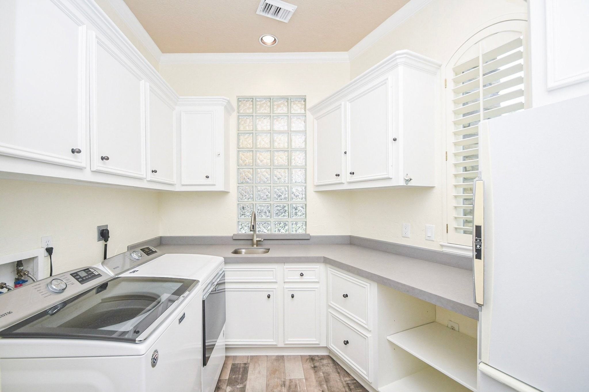 Large utility room conveniently located downstairs with tons of storage space, featuring ample cabinetry, workspace for folding, and easy access to the main living area!