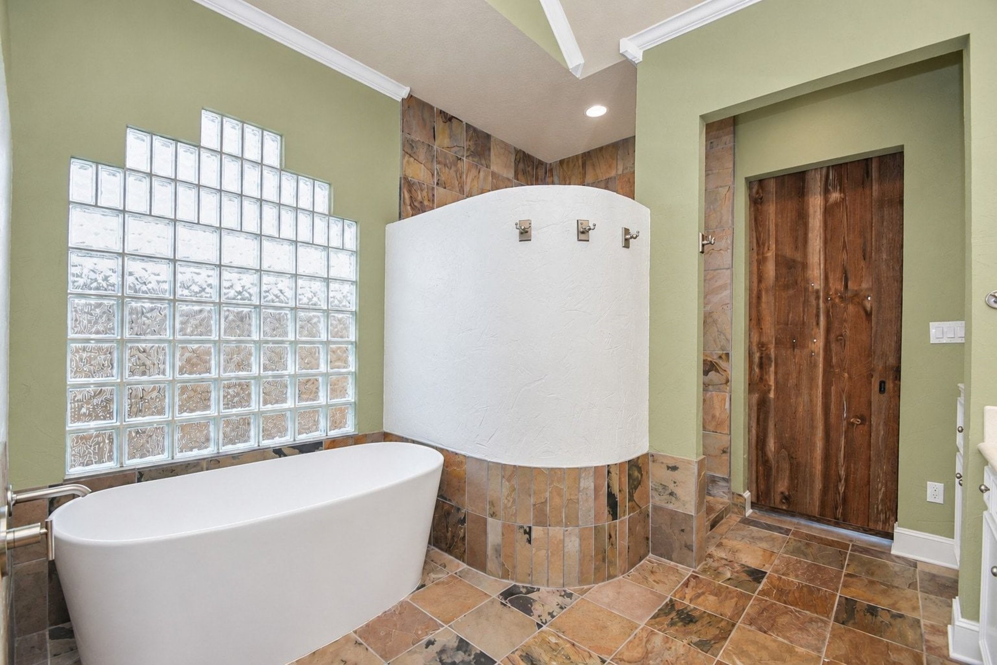 This luxurious primary bathroom offers a serene retreat, highlighting a spacious layout anchored by a large soaking tub and a sleek, custom walk-in shower. The room is further elevated by sophisticated vanity finishes, premium hardware, and ample counter space, all perfectly illuminated to create a bright, inviting atmosphere that emphasizes the home's high-end, spa-inspired design.