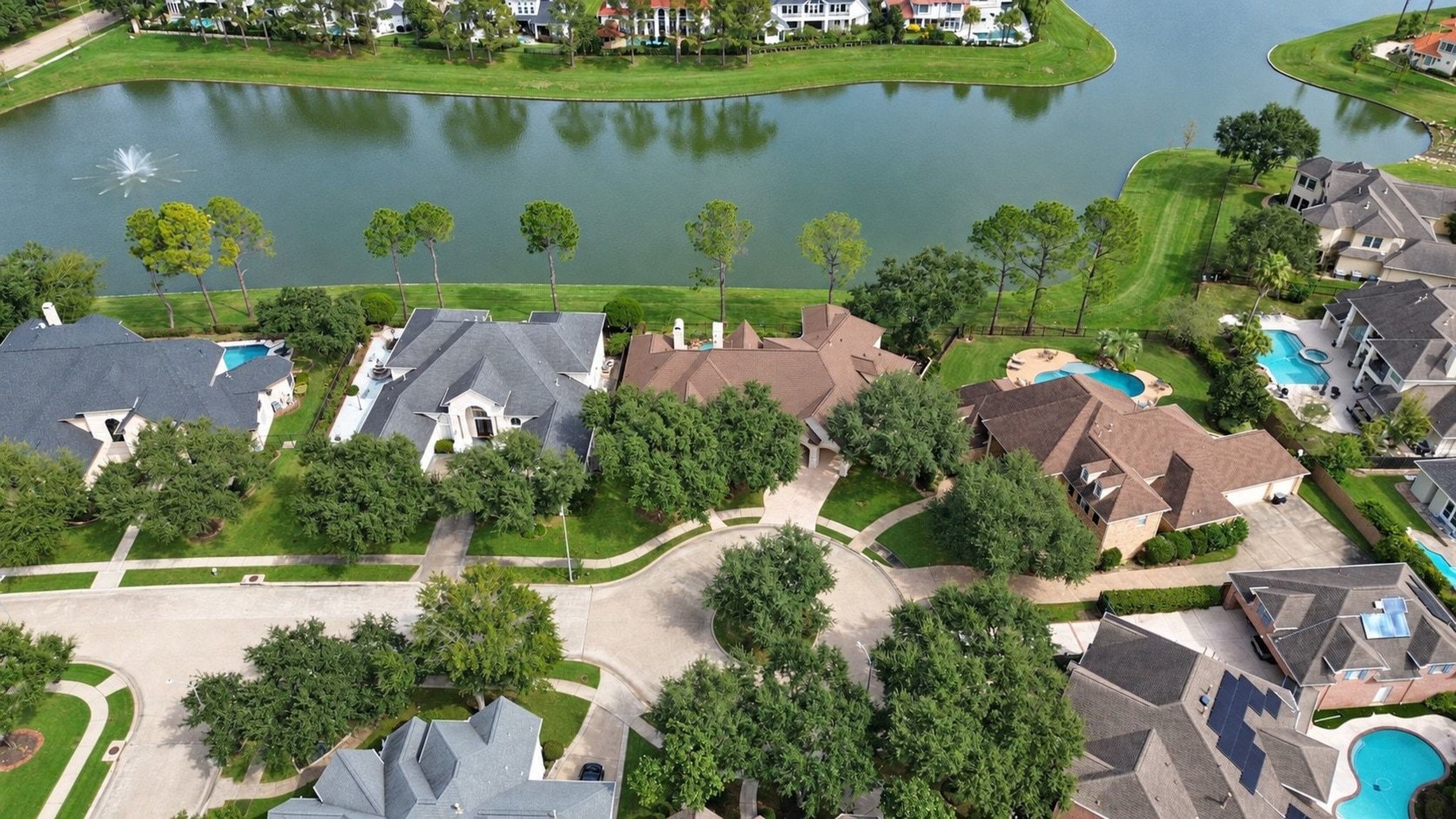 Stunning aerial perspective capturing the expansive, serene lake and the charming surrounding neighborhood, offering a perfect blend of natural beauty and an enviable lifestyle location!